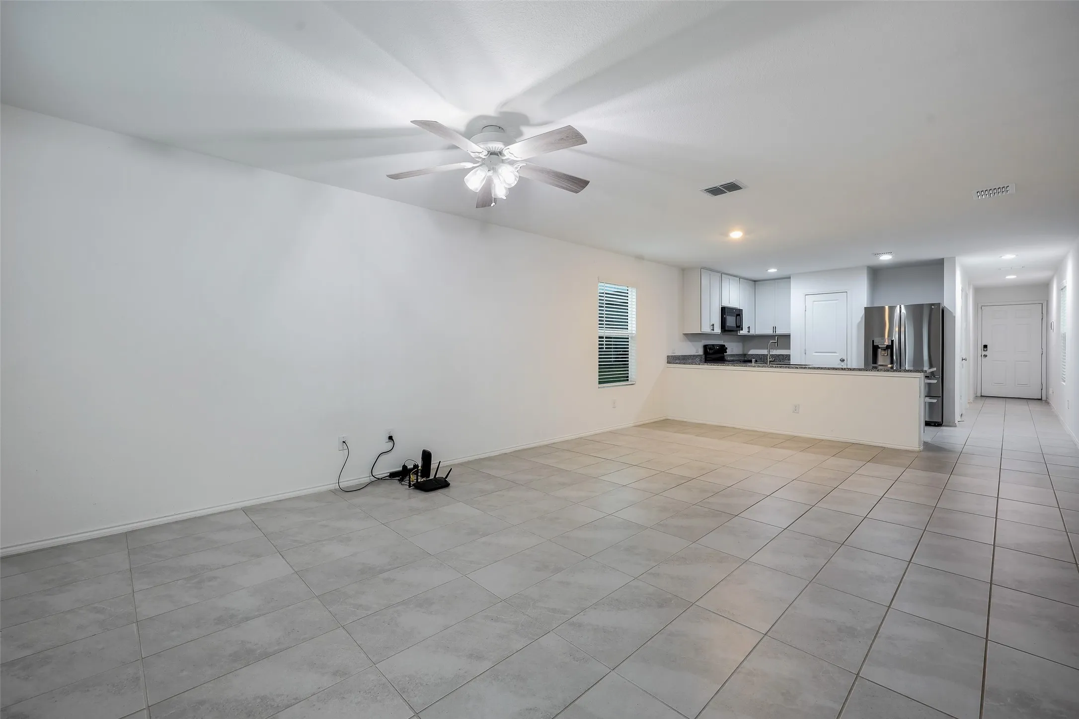 Expansive tiled flooring throughout, modern ceiling fan, recessed lighting, and a kitchen featuring stainless steel appliances and light-toned cabinetry