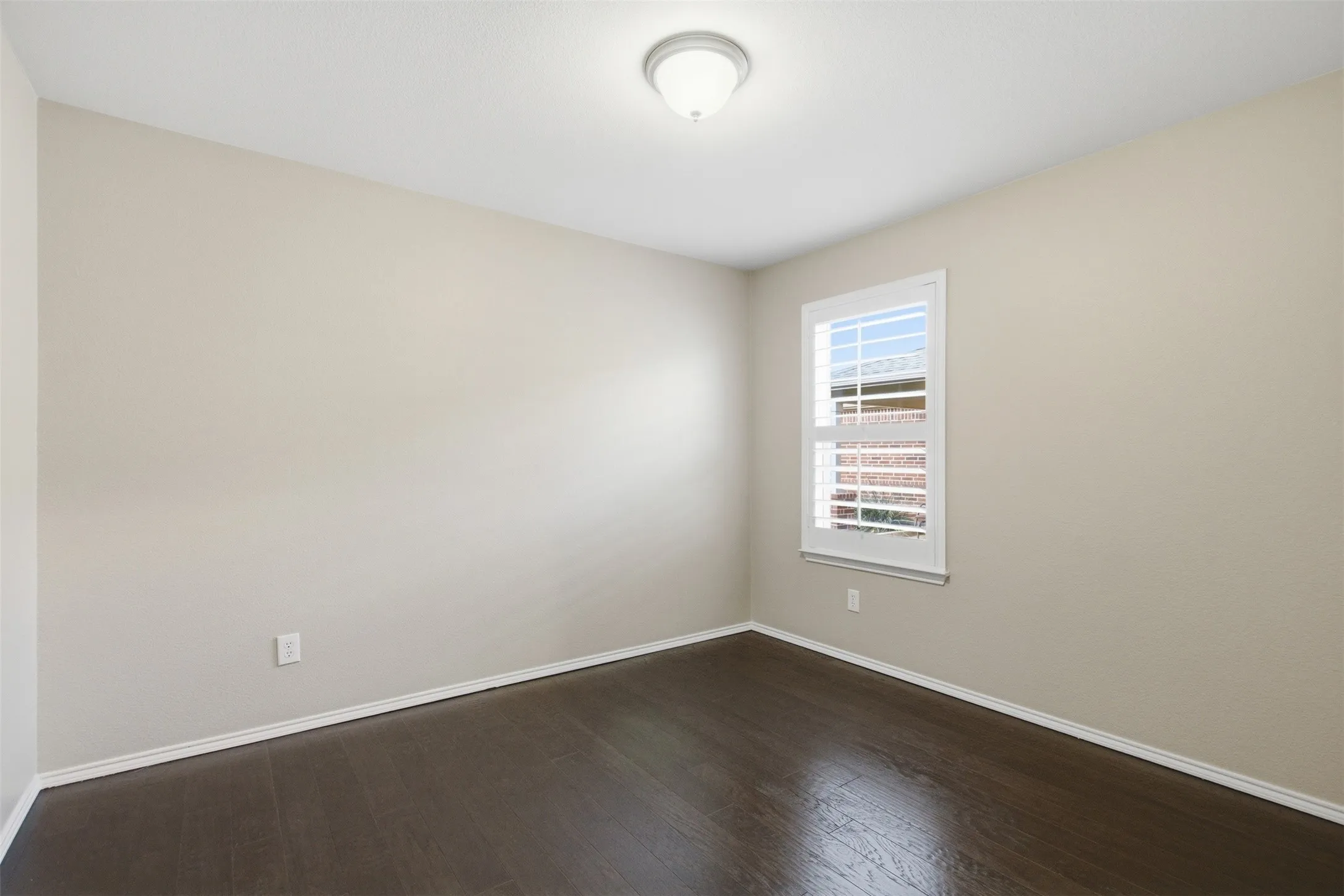 Recessed ceiling light, hard surface flooring, neutral wall tones, window with white plantation shutters, and white trim