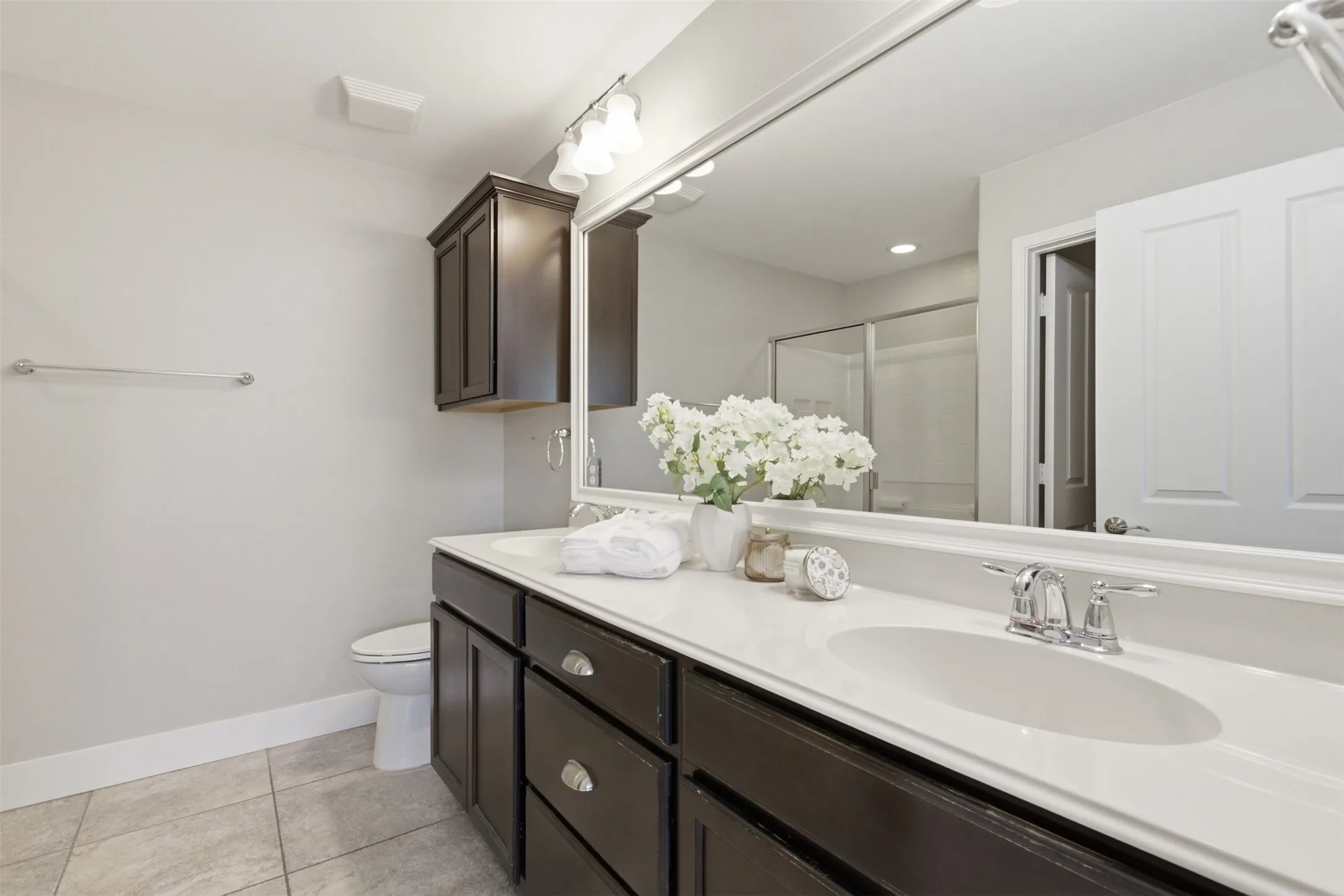 Dual vanity with dark wood-finish cabinetry, chrome hardware, and white countertops