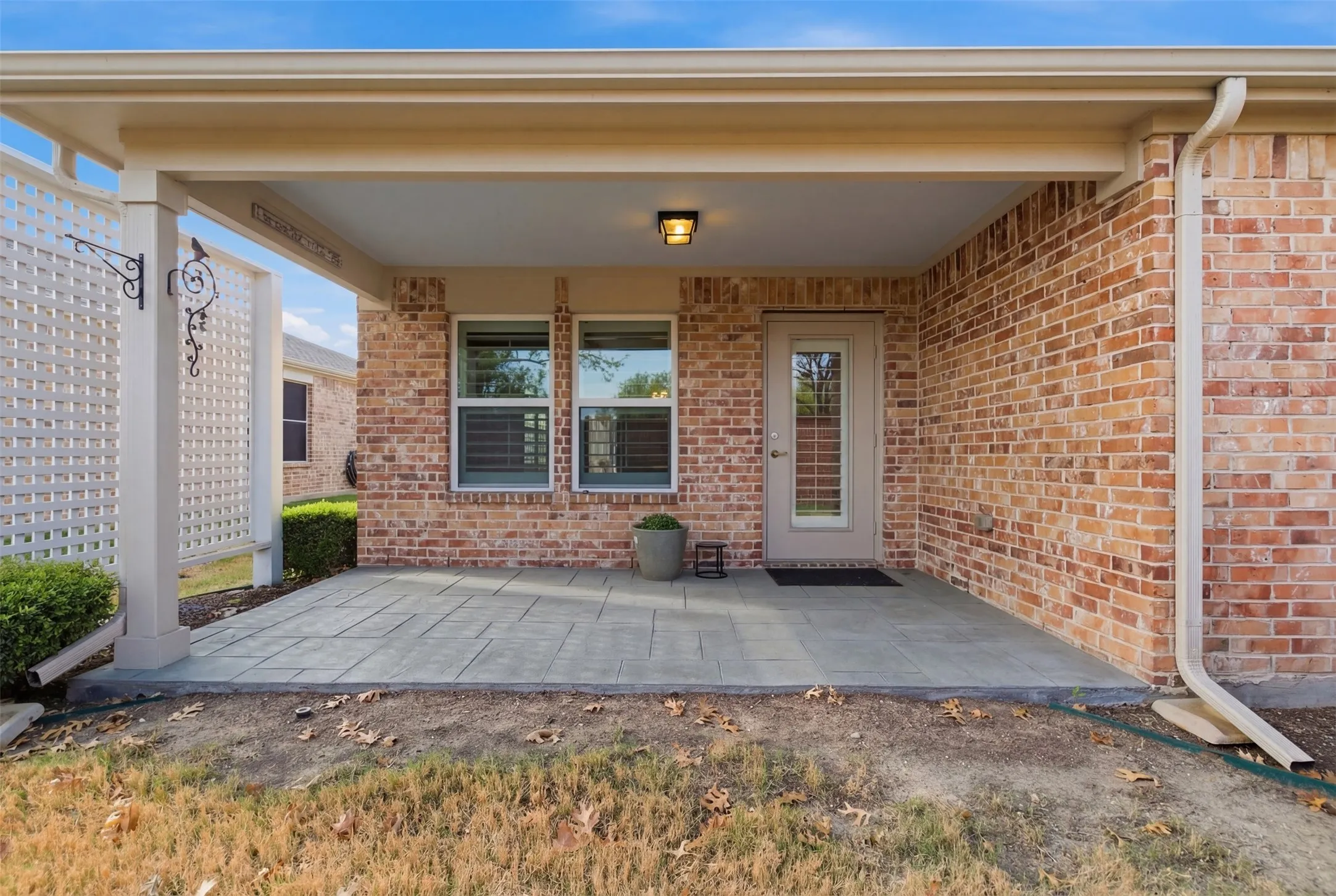 Covered patio featuring a brick exterior and a lattice privacy screen