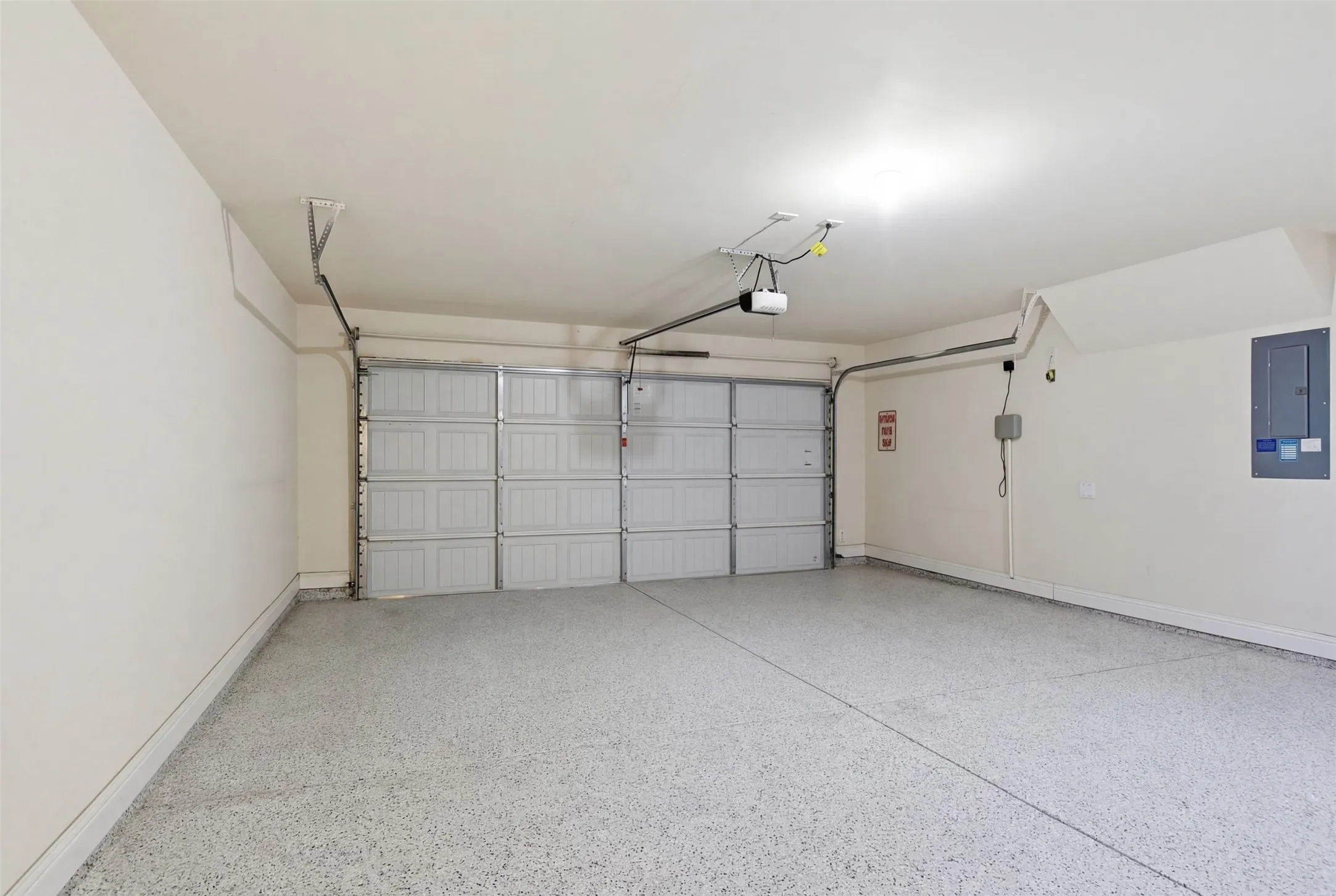 Garage with an overhead garage door, epoxy-coated flooring, and overhead lighting