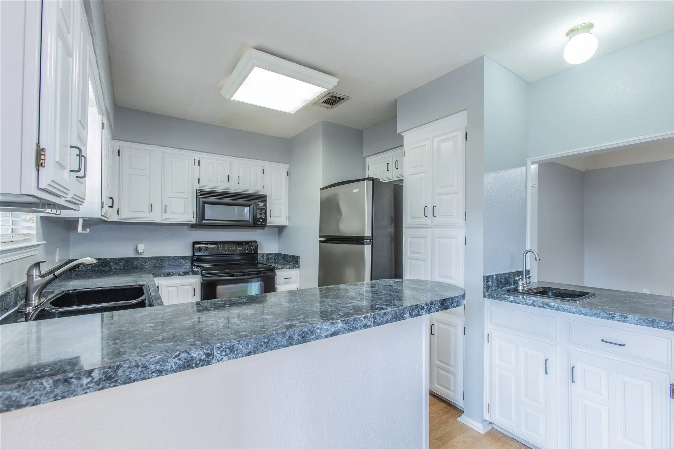 Kitchen featuring white cabinetry, dark countertops, a stainless steel refrigerator, and built-in​​‌​​​​‌​​‌‌​‌‌​​​‌‌​‌​‌​‌​​​‌​​ microwave