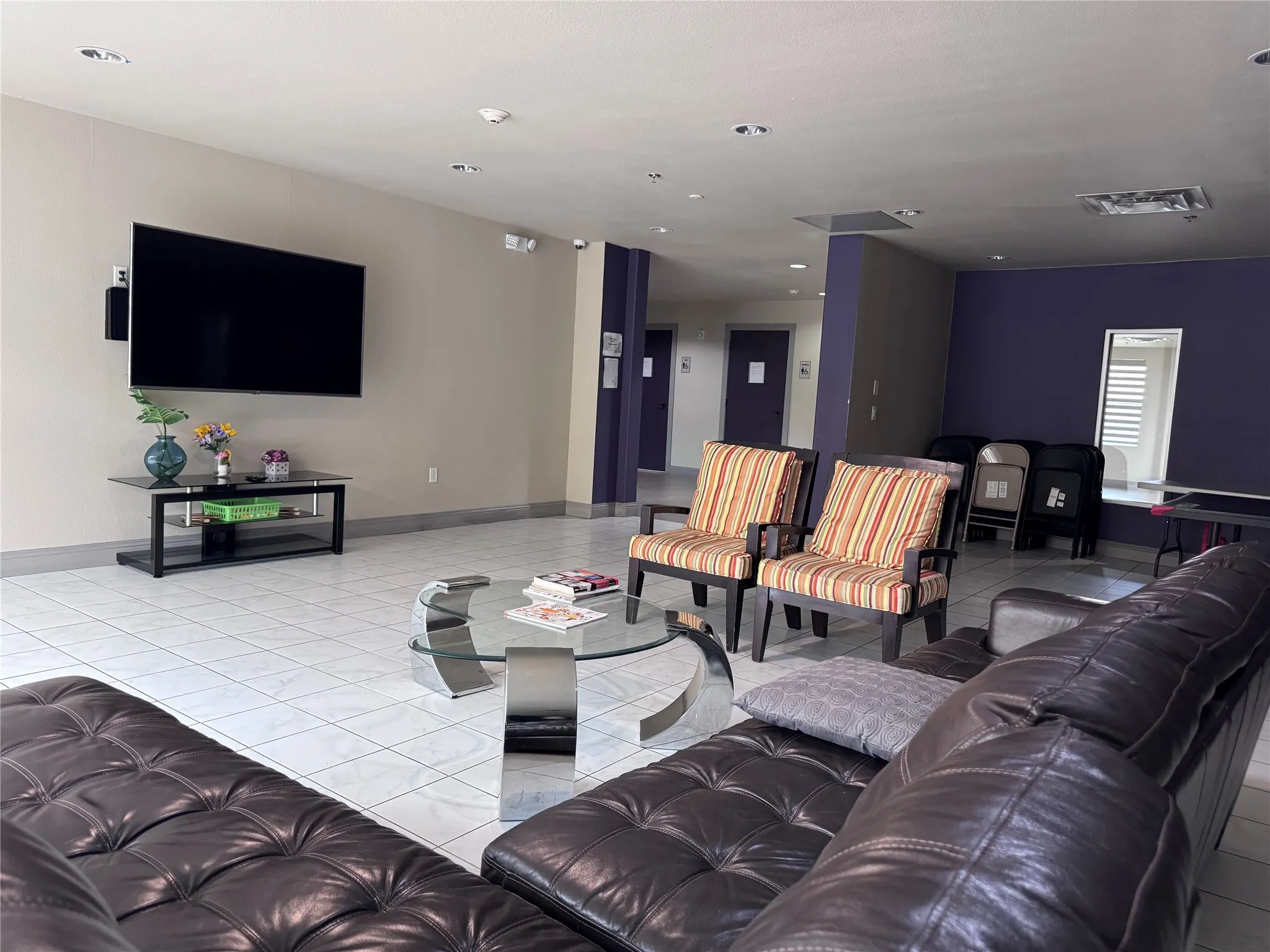 Tiled flooring with recessed lighting, complemented by a wall-mounted television and integrated speakers