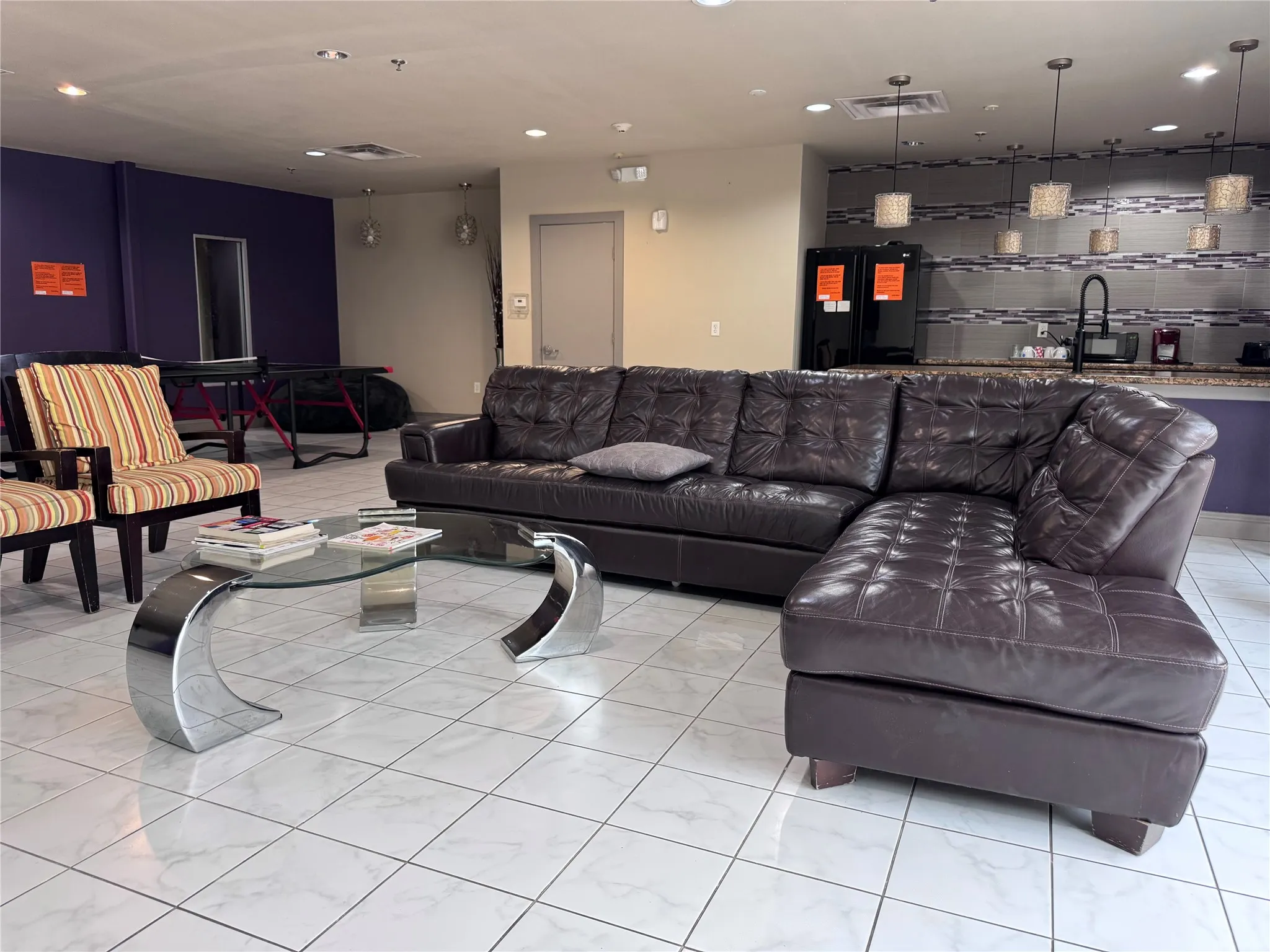 Expansive open-concept room featuring square tile flooring, recessed lighting, and a built-in wet bar with a tiled backsplash and pendant lighting
