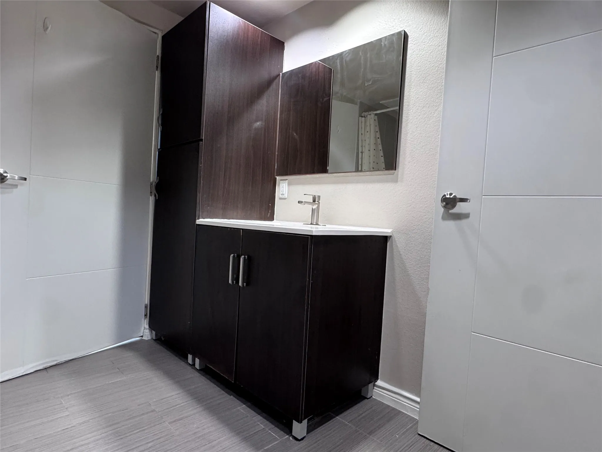 Vanity with integrated sink, dark wood-finish cabinetry, and brushed nickel hardware