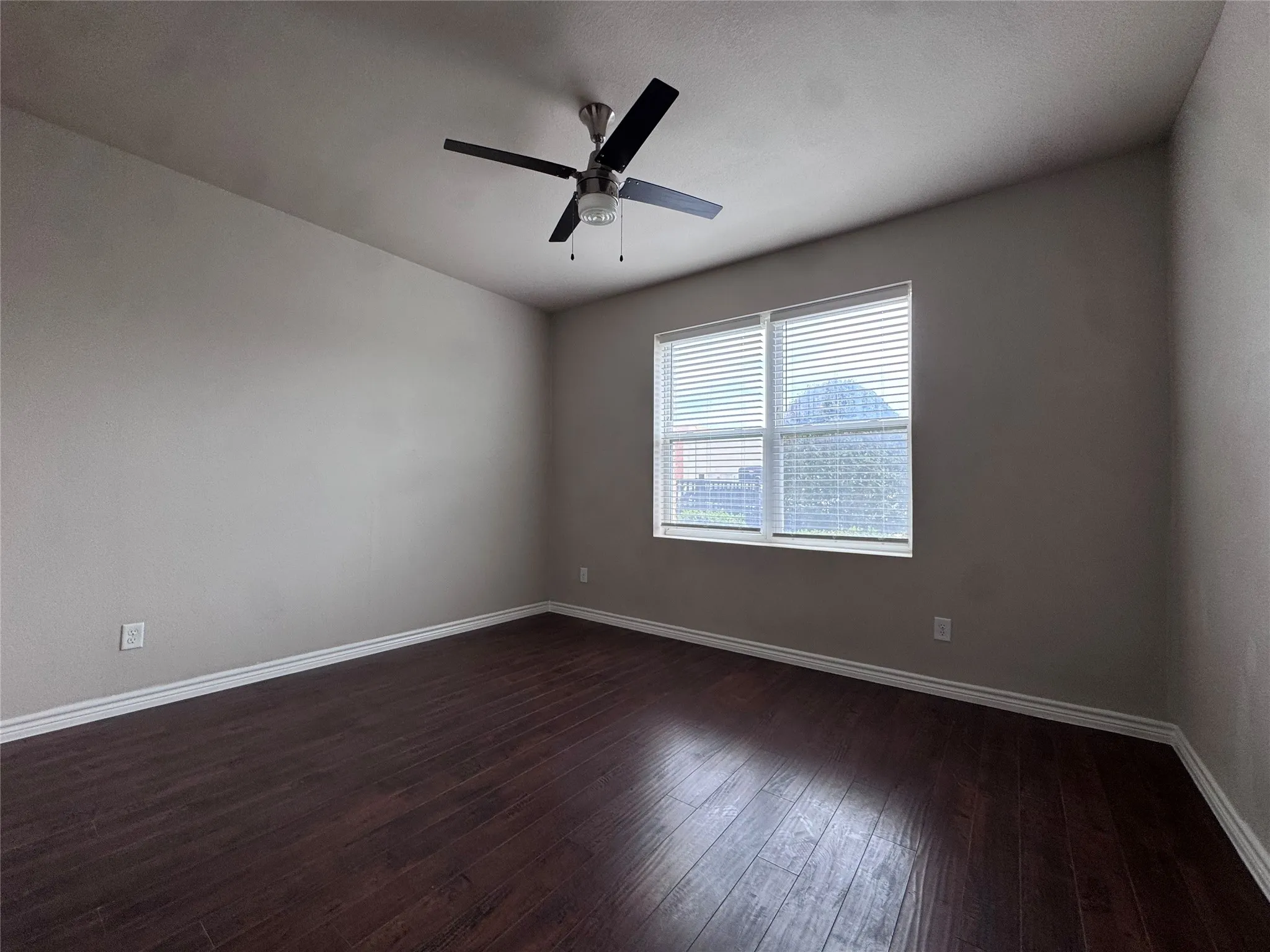Wood-finish flooring, neutral wall color, ceiling fan with integrated lighting, and window with blinds