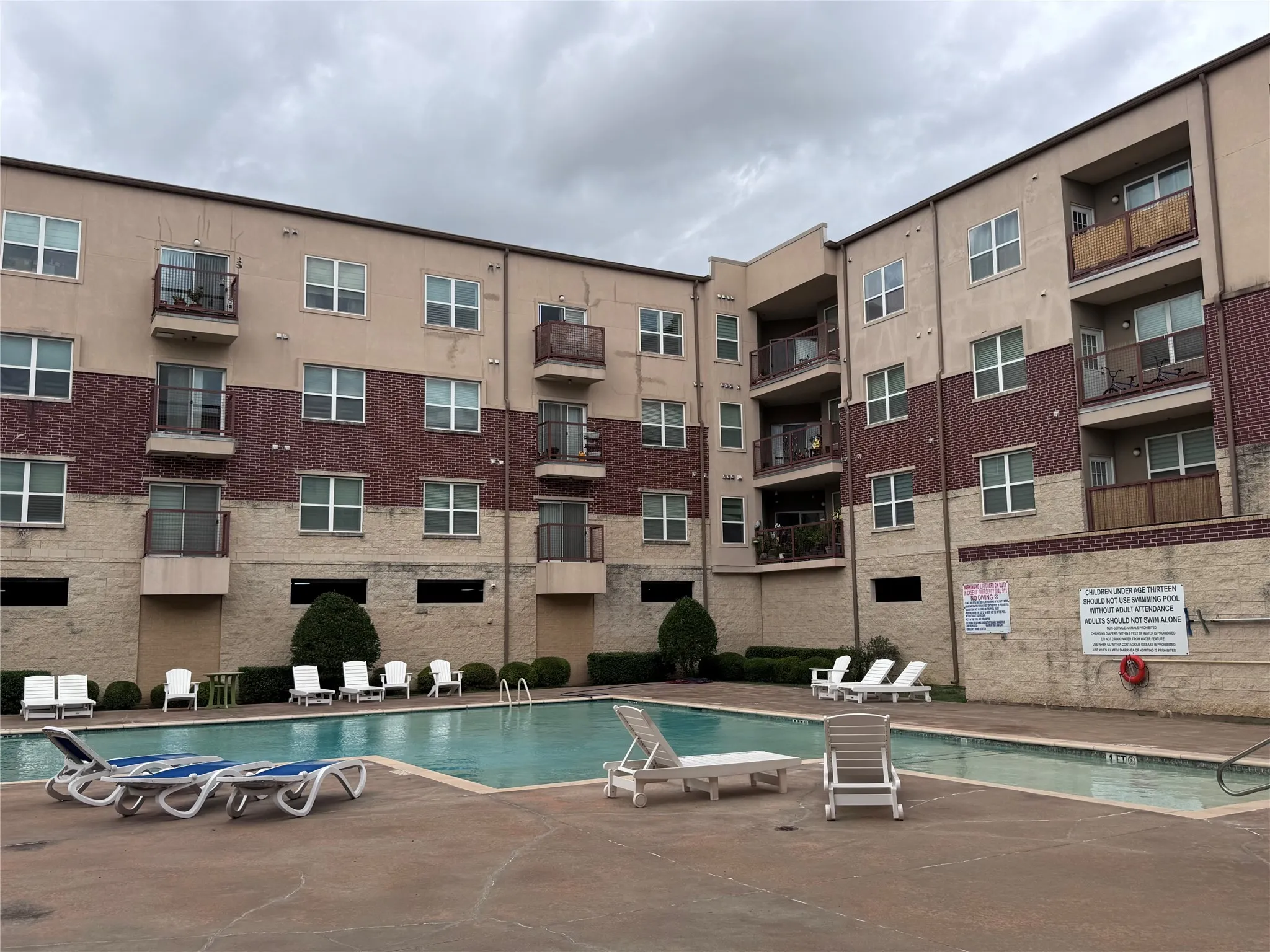 Building exterior featuring a swimming pool, multiple balconies, and brick accent panels