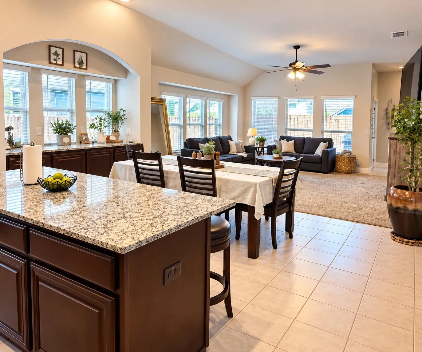 Granite-topped kitchen island with dark wood cabinetry, tile flooring, vaulted ceiling, and multiple windows
