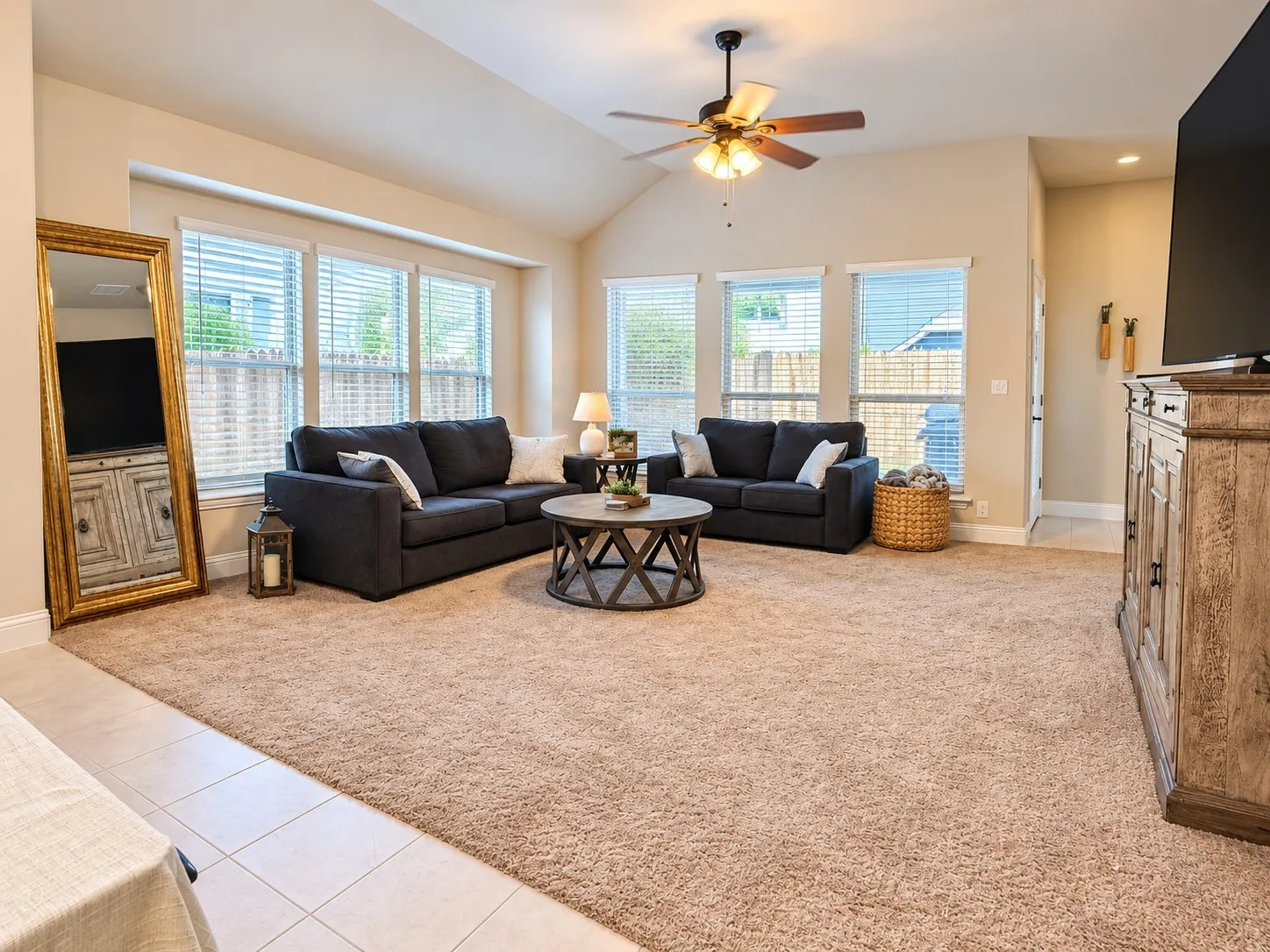 Vaulted ceiling with a ceiling fan, multiple windows with blinds, and light-colored wall finishes