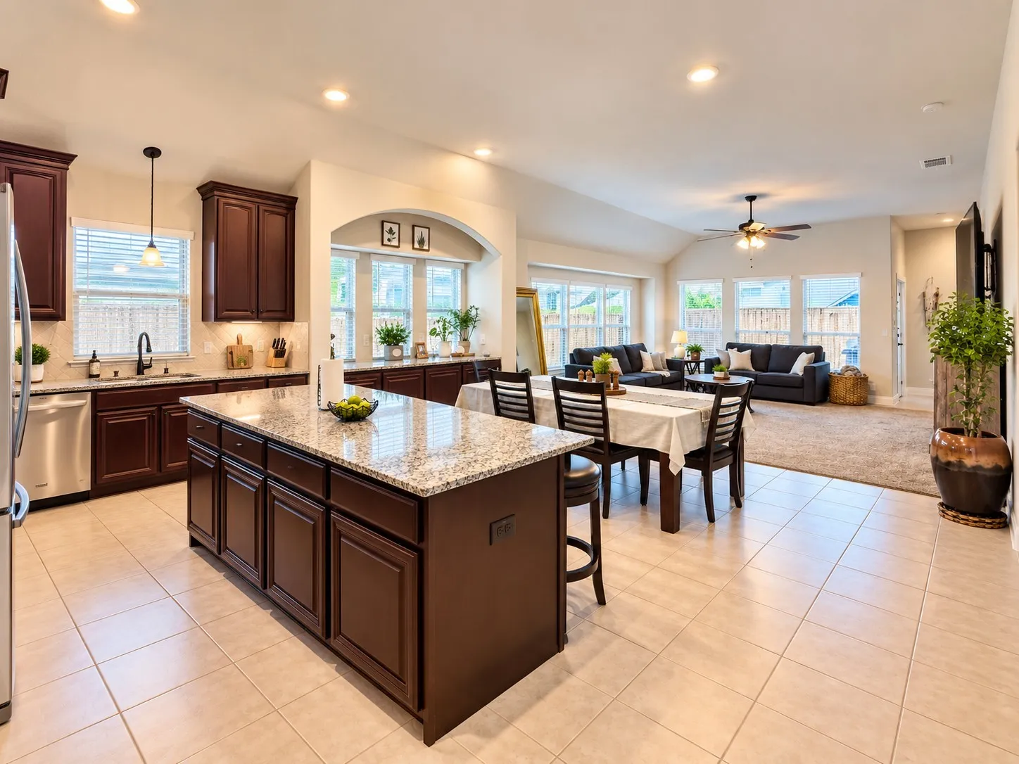 Kitchen island with granite countertop, recessed lighting, stainless steel appliances, dark wood cabinetry, and tile flooring