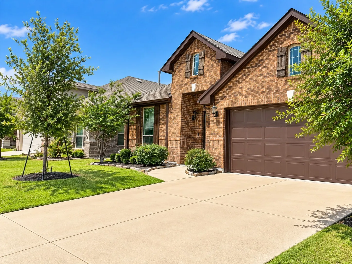 Brick exterior with arched window accents, brown garage door, and a concrete driveway