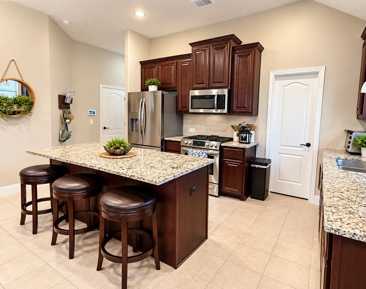 Kitchen featuring an expansive island with a light-toned countertop, wood-finish cabinetry, stainless steel appliances, and tile flooring