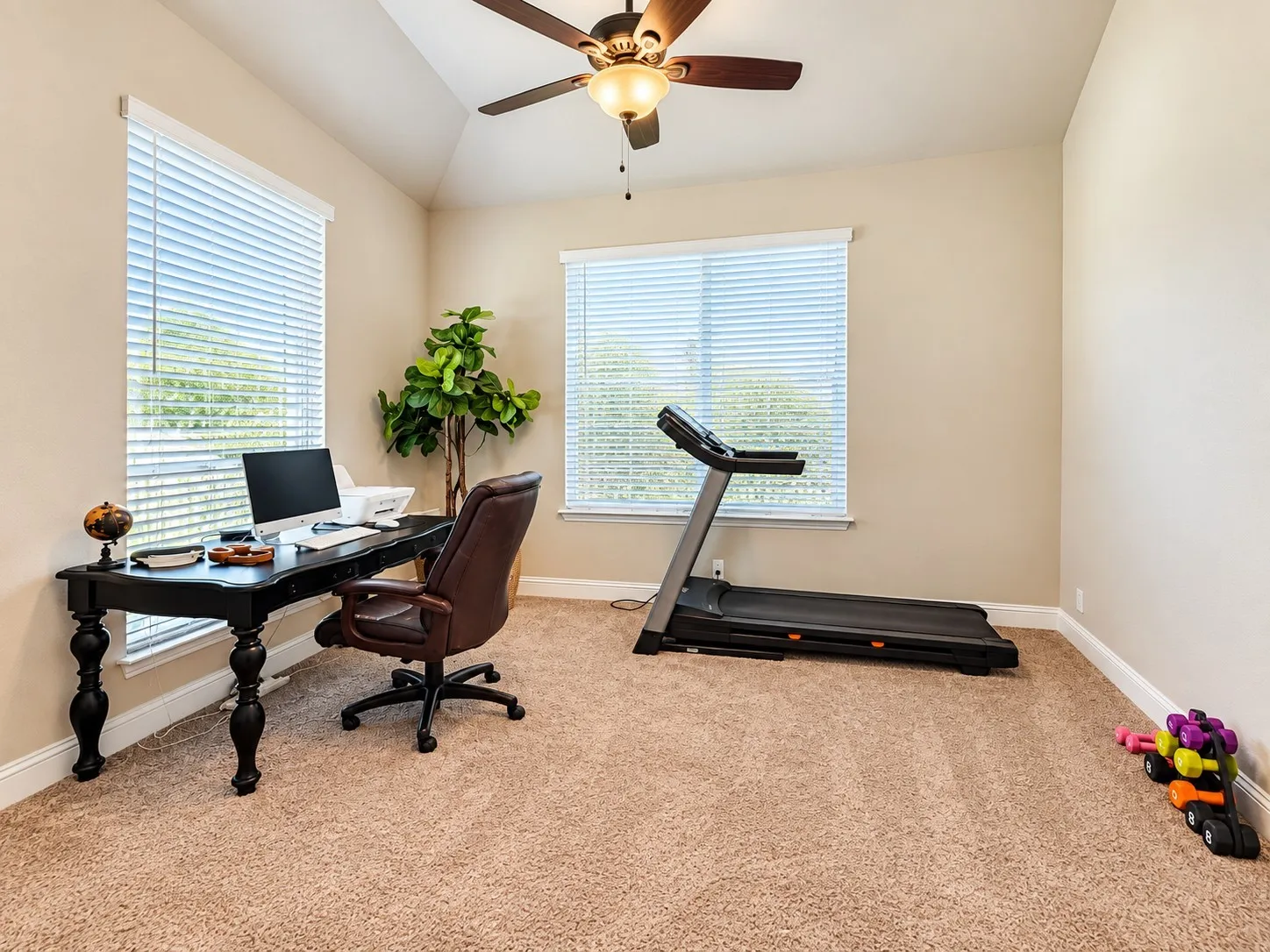 Carpeted room with a vaulted ceiling, ceiling fan with integrated lighting, and multiple windows with blinds
