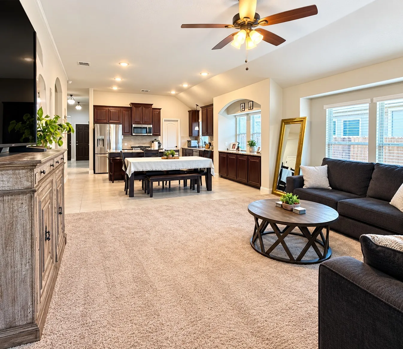 Vaulted ceiling with recessed lighting and a ceiling fan, spacious kitchen with dark wood-finish cabinetry and stainless steel appliances, and a dining area with tile flooring
