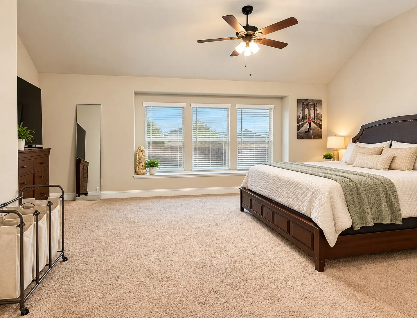 Vaulted ceiling with a ceiling fan, carpeted flooring, three large windows, and a built-in window ledge