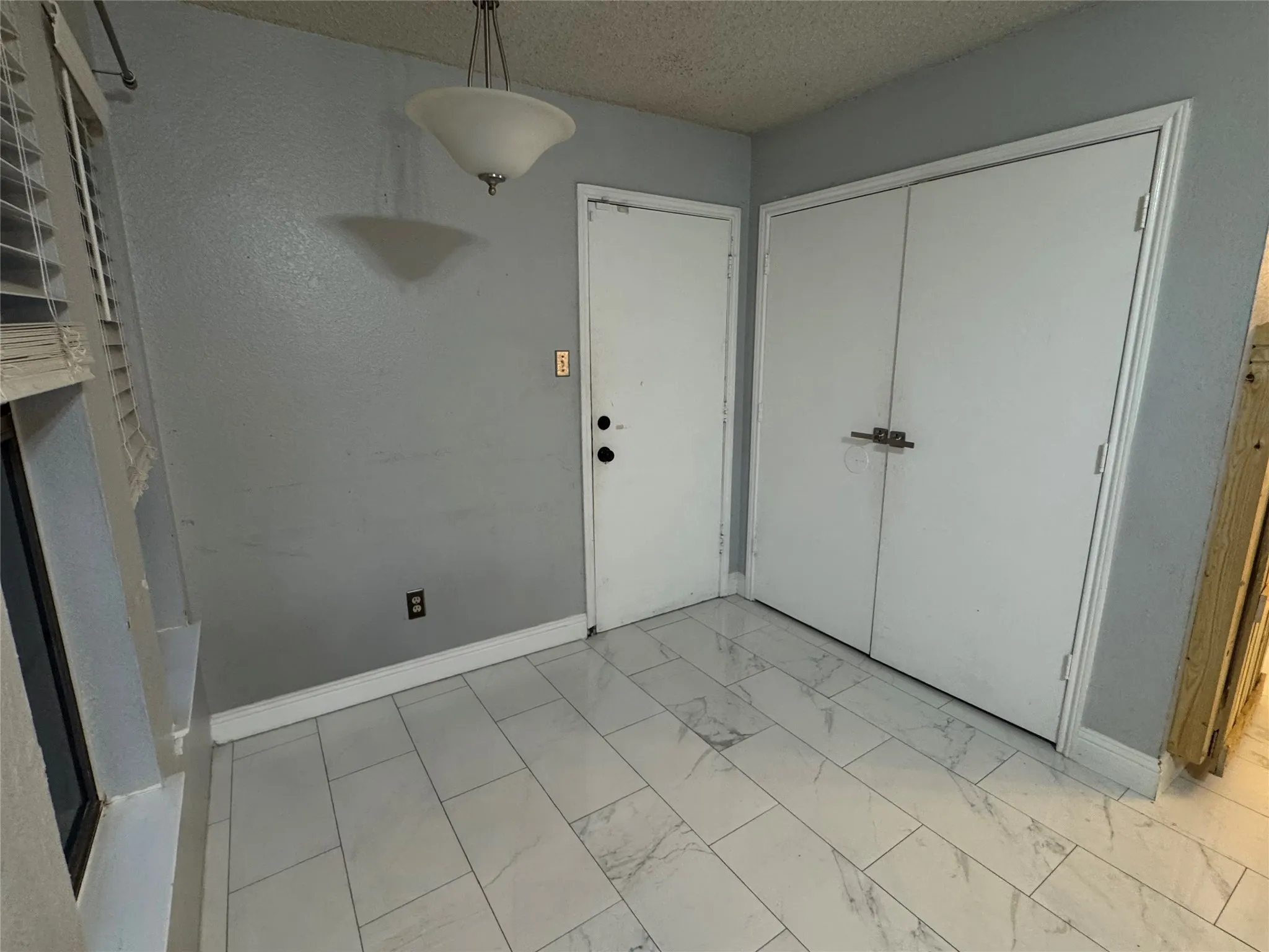 White tile flooring, ceiling-mounted light fixture, and white bi-fold doors