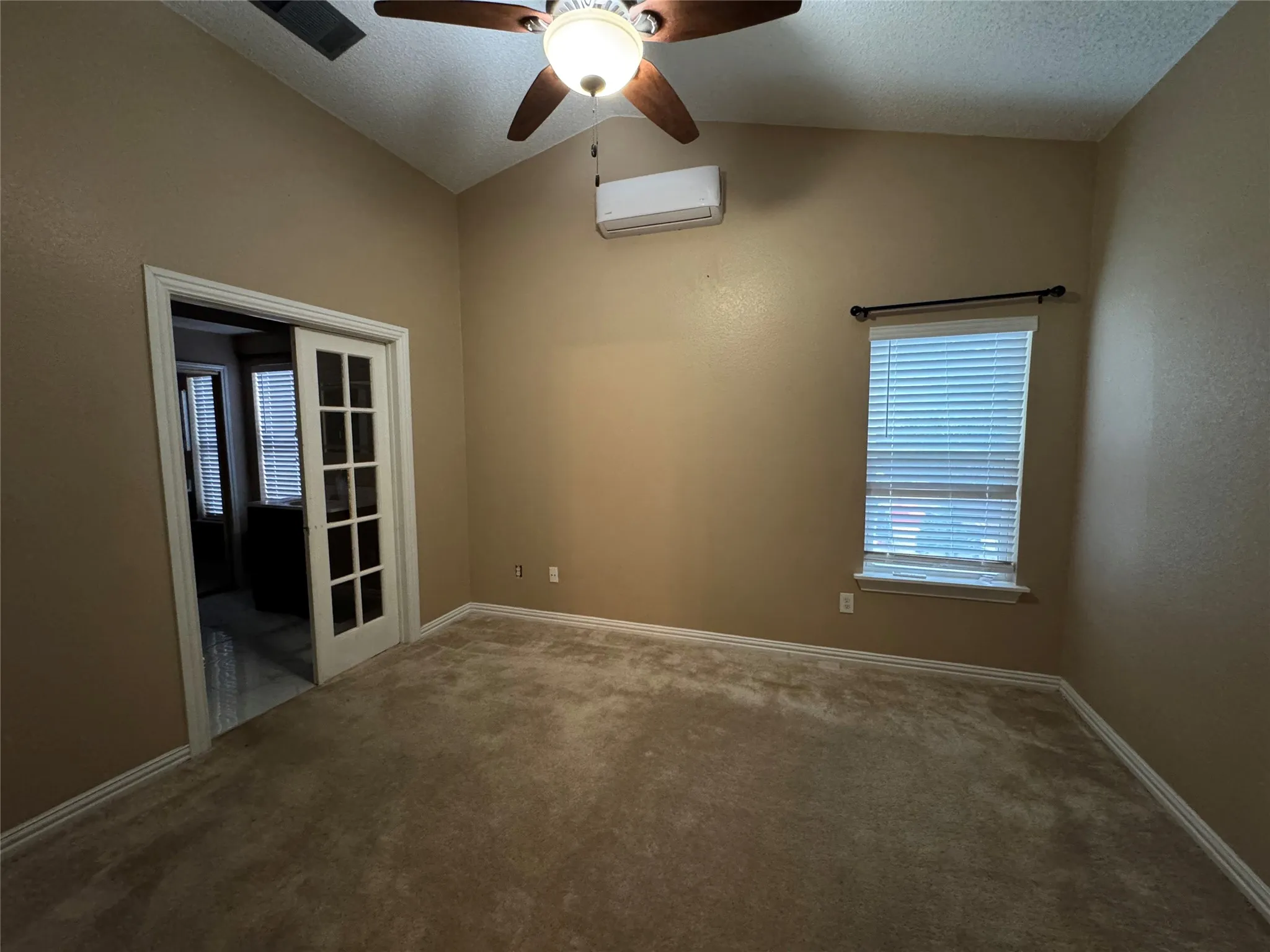 Vaulted ceiling featuring a ceiling fan with integrated lighting, a window with blinds, and French doors