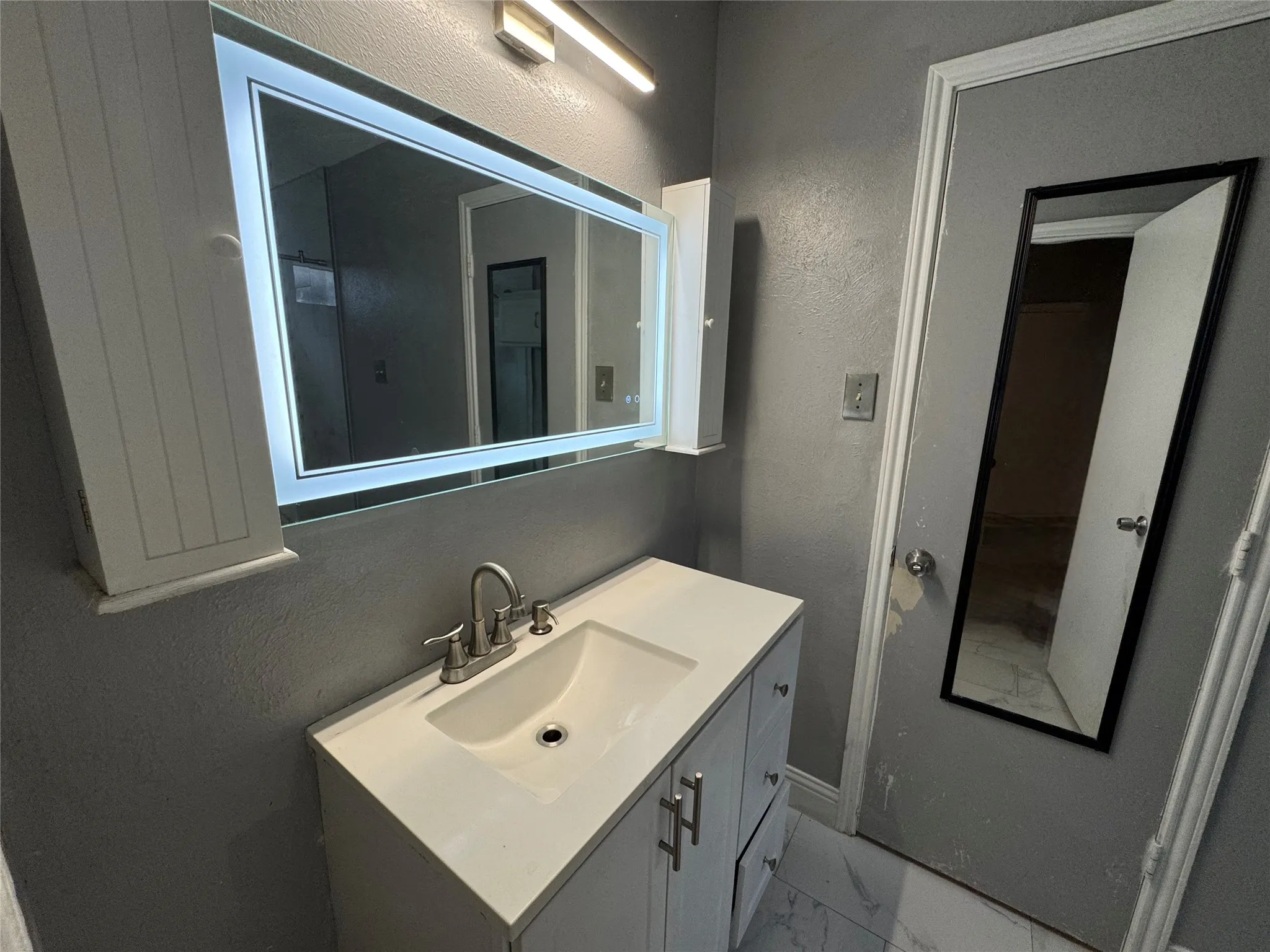 White vanity with a single basin sink, brushed nickel faucet, and integrated countertop