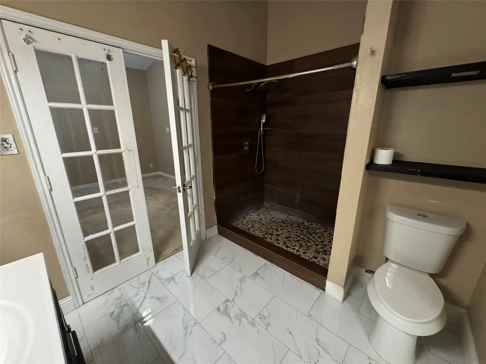 Walk-in shower with pebble tile floor and wood-finish wall tile