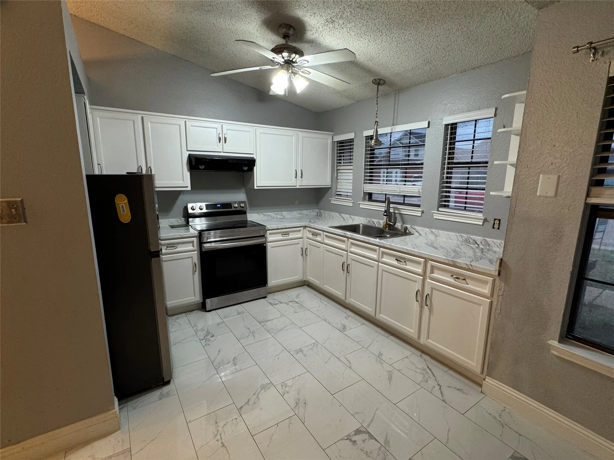 Kitchen featuring white cabinetry, stainless steel range, white marble-look countertops, and white tile flooring
