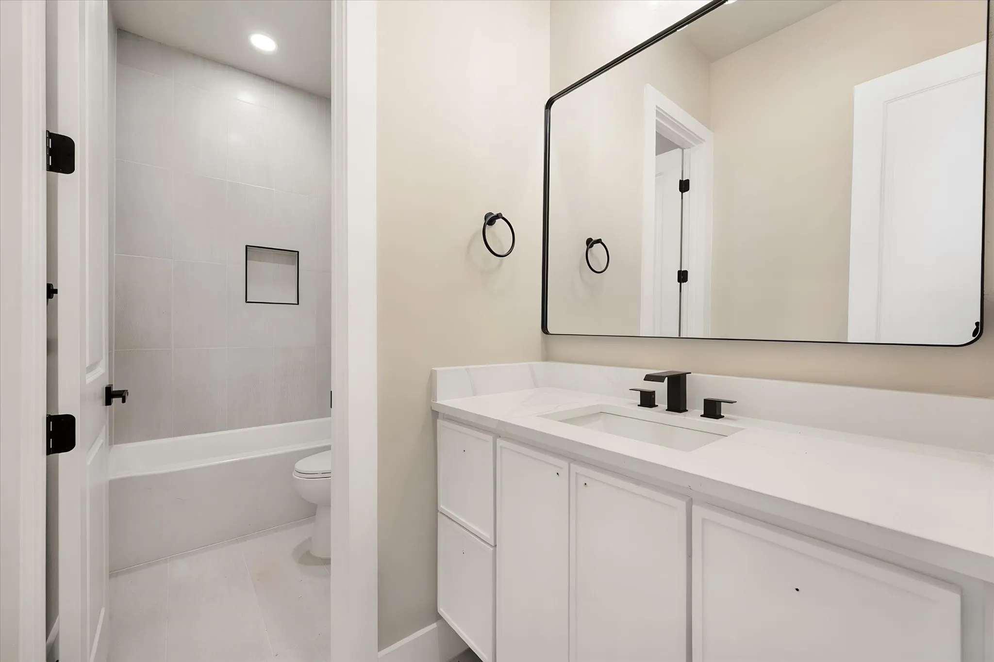 White vanity with a solid surface countertop, undermount sink, and matte black fixtures