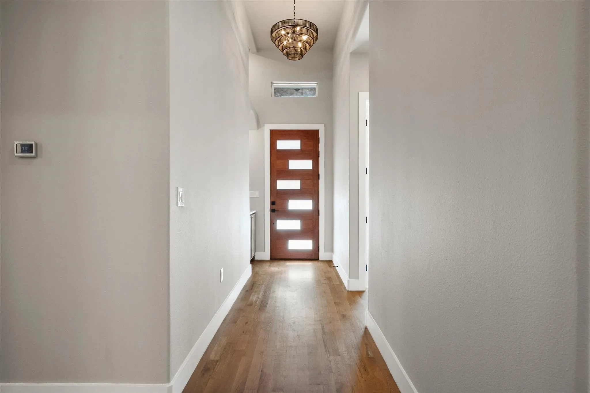 Wood-finish flooring, recessed lighting, and a modern chandelier