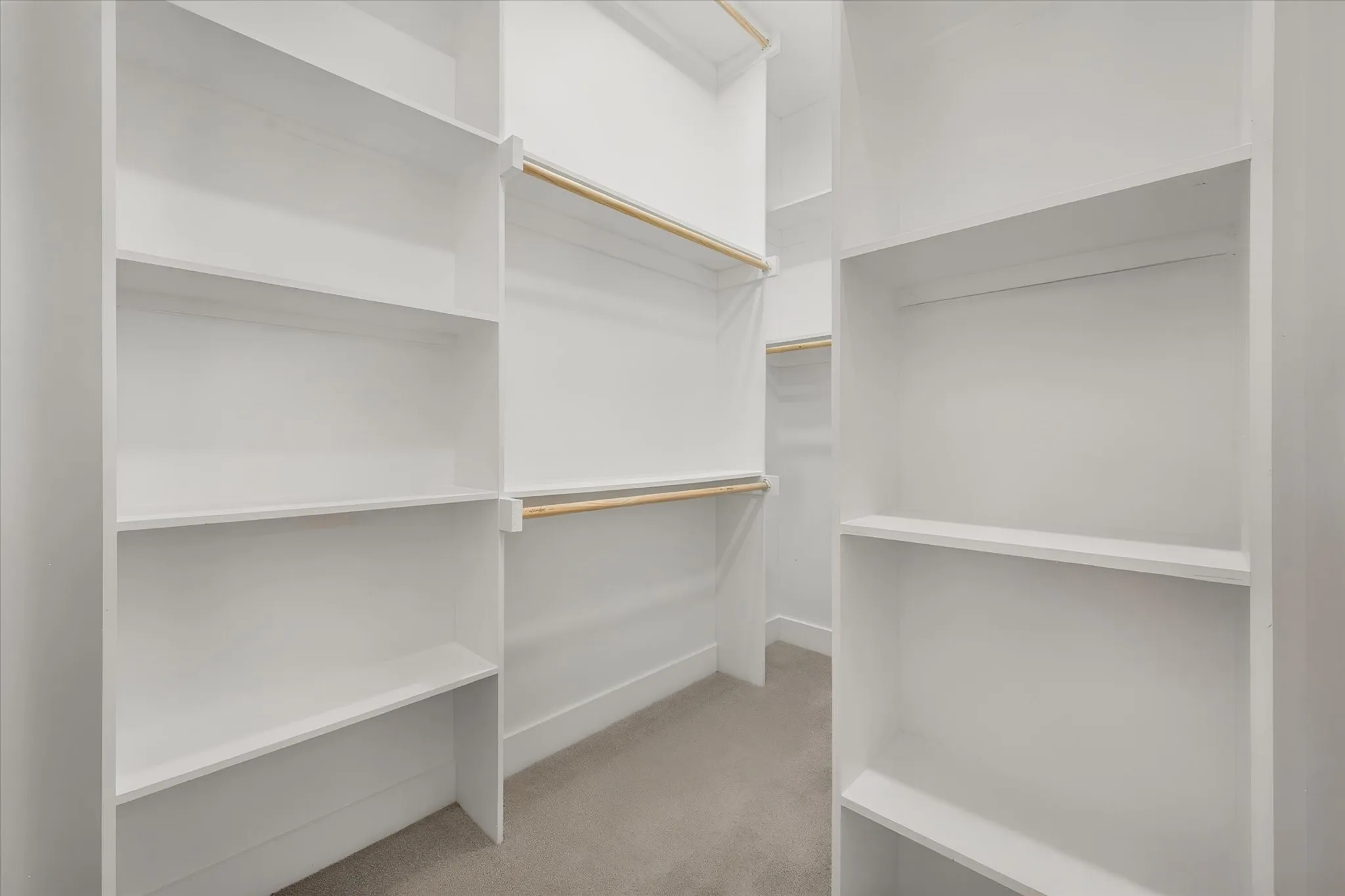 Built-in closet shelving, integrated hanging rods, and light-tone carpeting