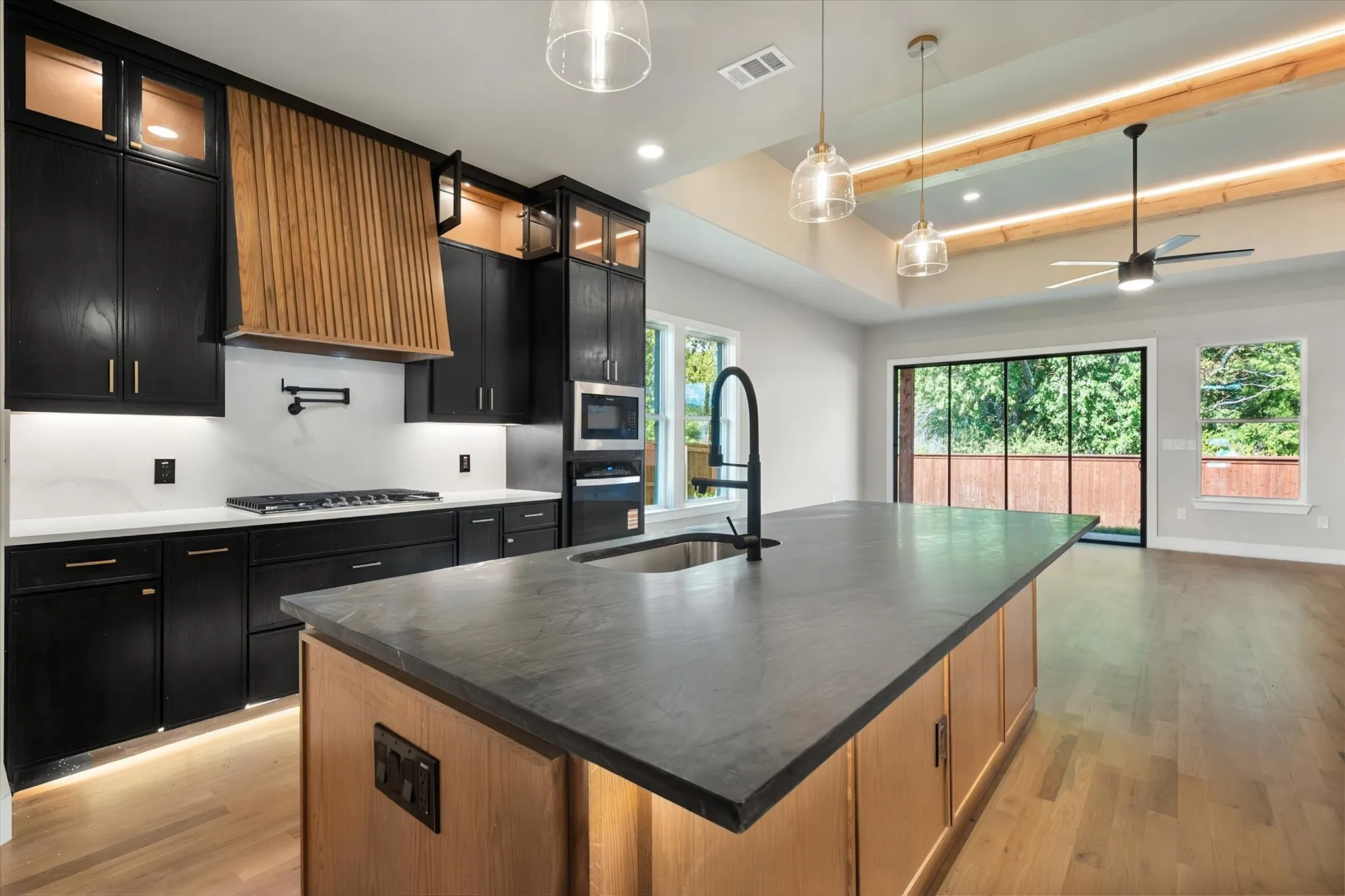 Gourmet kitchen with black cabinetry, wood-finish island, and white countertops