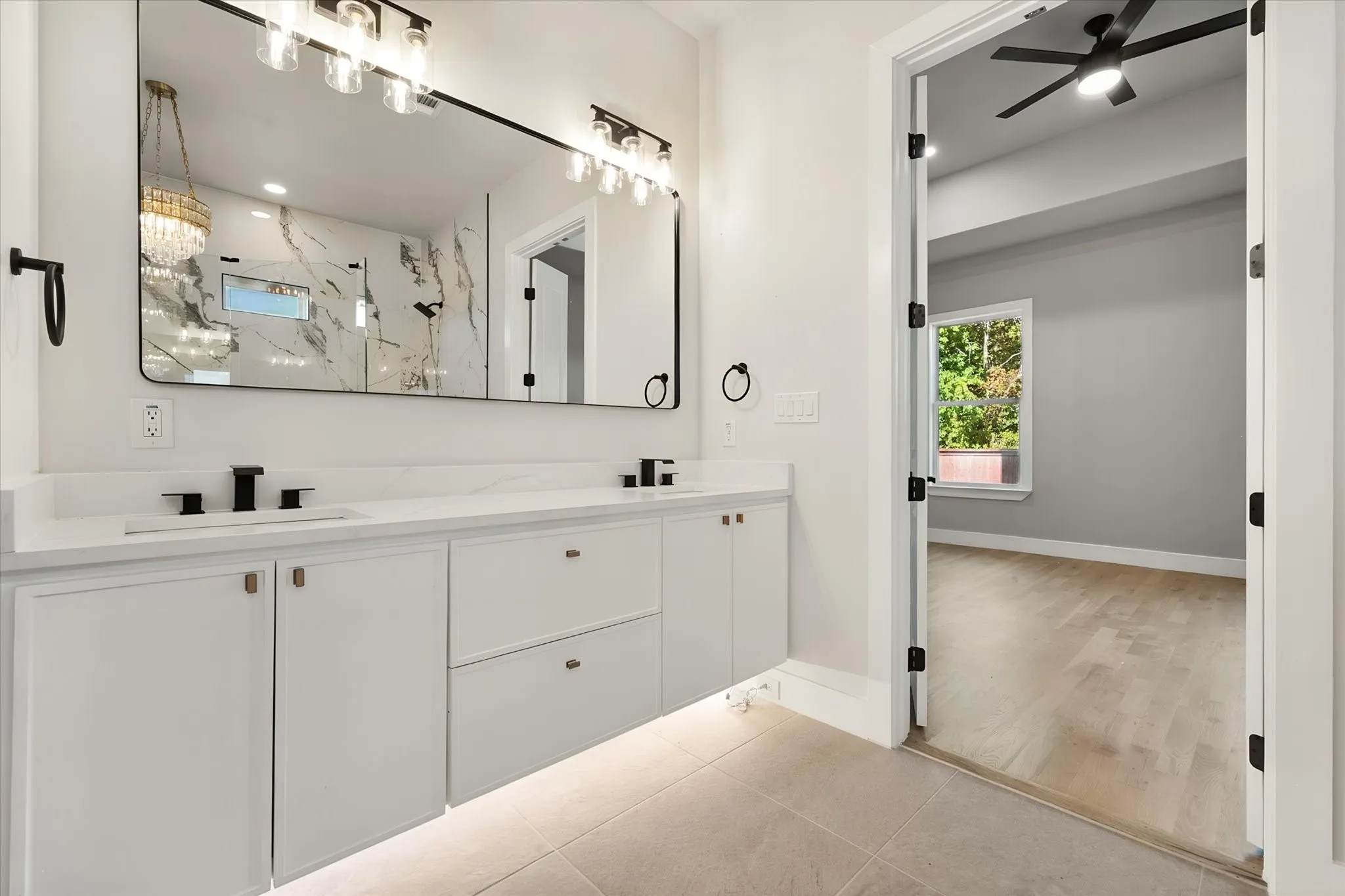 Dual vanity with white cabinetry, matte black hardware, and a large framed​​‌​​​​‌​​‌‌​‌‌​​​‌‌​‌​‌​‌​​​‌​​ mirror