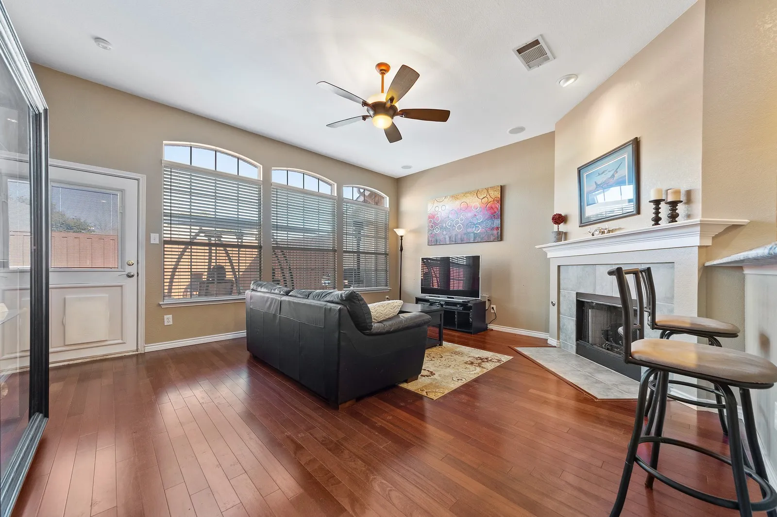Wood-finish flooring, recessed lighting, and a ceiling fan enhance this living space