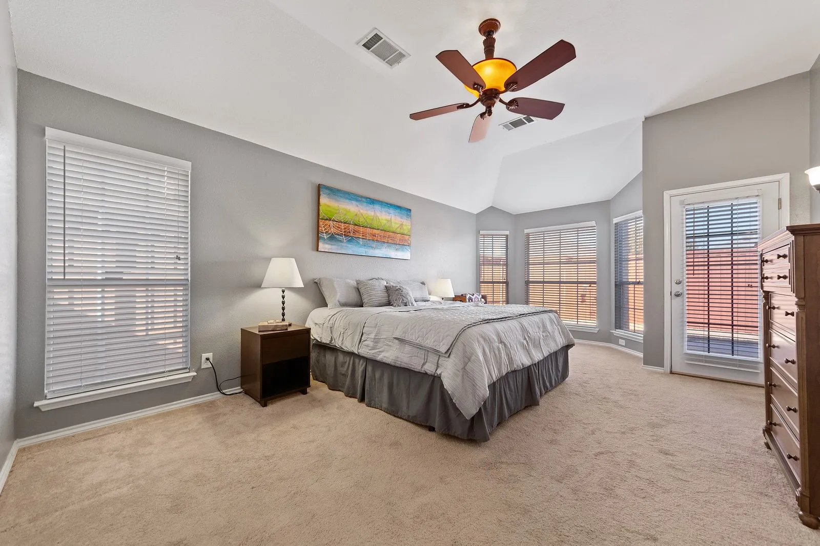 Tray ceiling with a ceiling fan light fixture, multiple windows with blinds, and a glass-paneled door