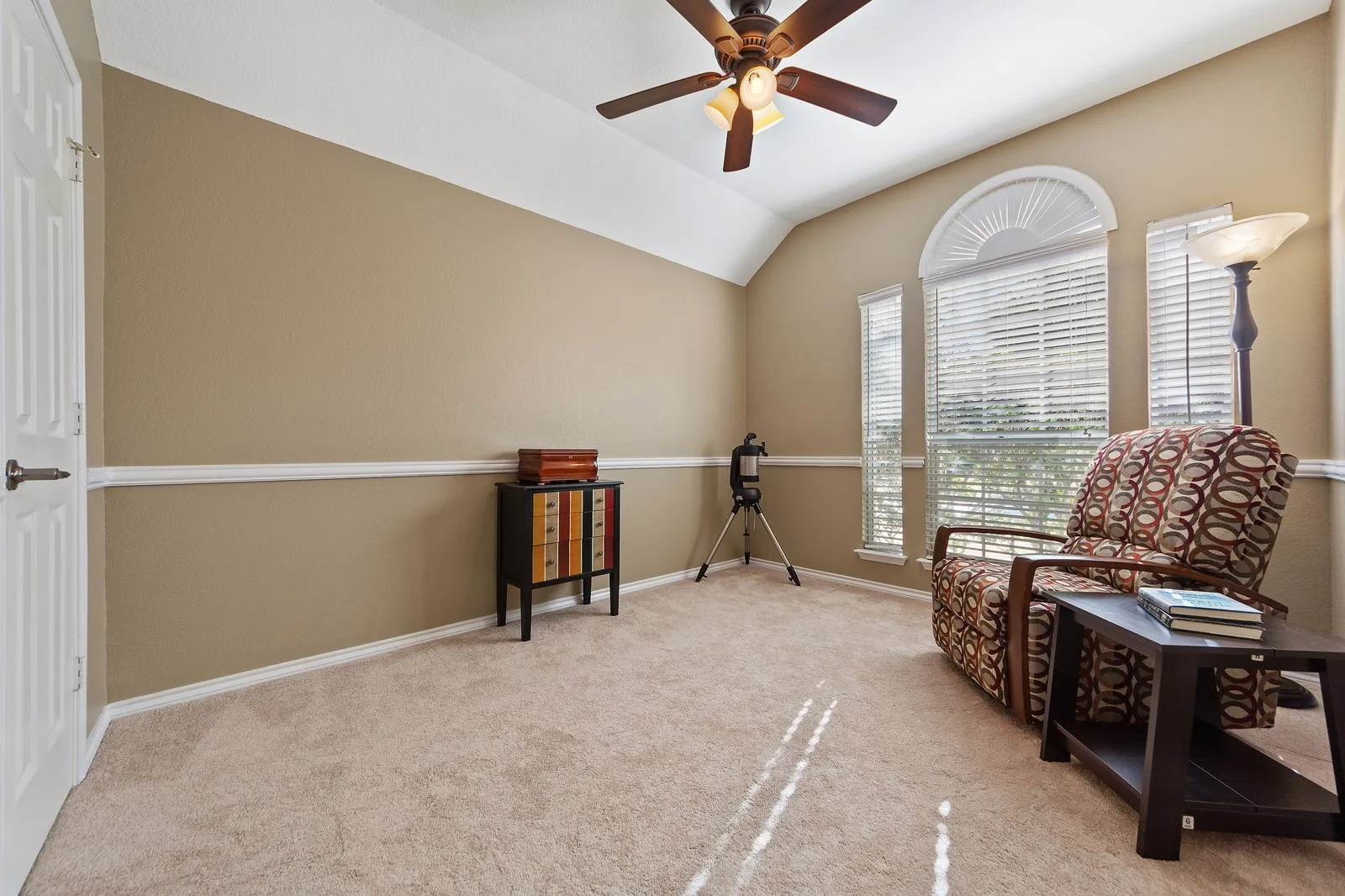 Vaulted ceiling with a ceiling fan, arched transom window, and paneled interior door