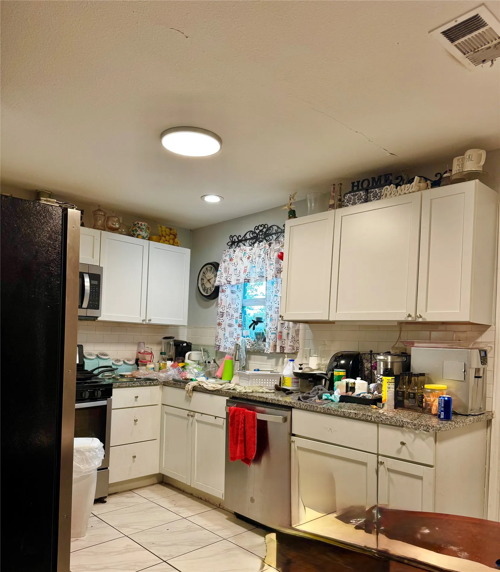 White cabinetry, stainless steel appliances, tile flooring, window with natural light, and recessed lighting