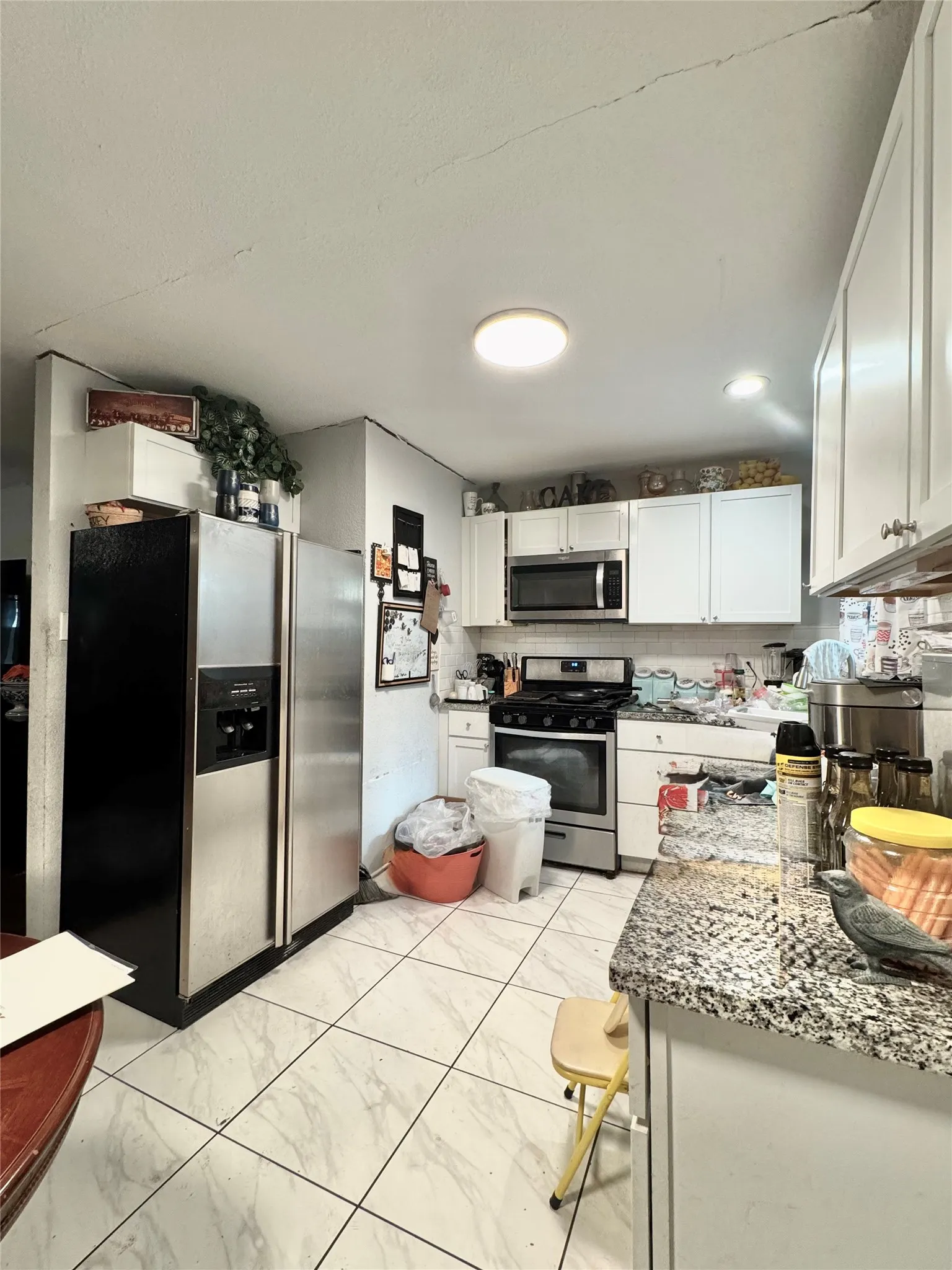 White cabinetry, granite-style countertops, stainless steel appliances, and tile flooring