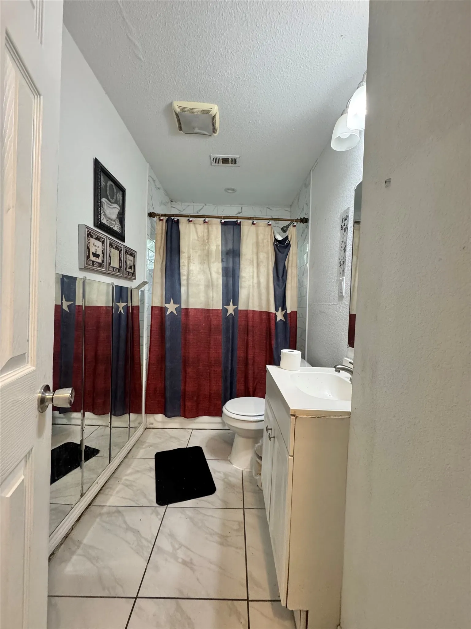 White panel door leading to a bathroom featuring a toilet, white vanity with integrated sink, and a tiled shower enclosure