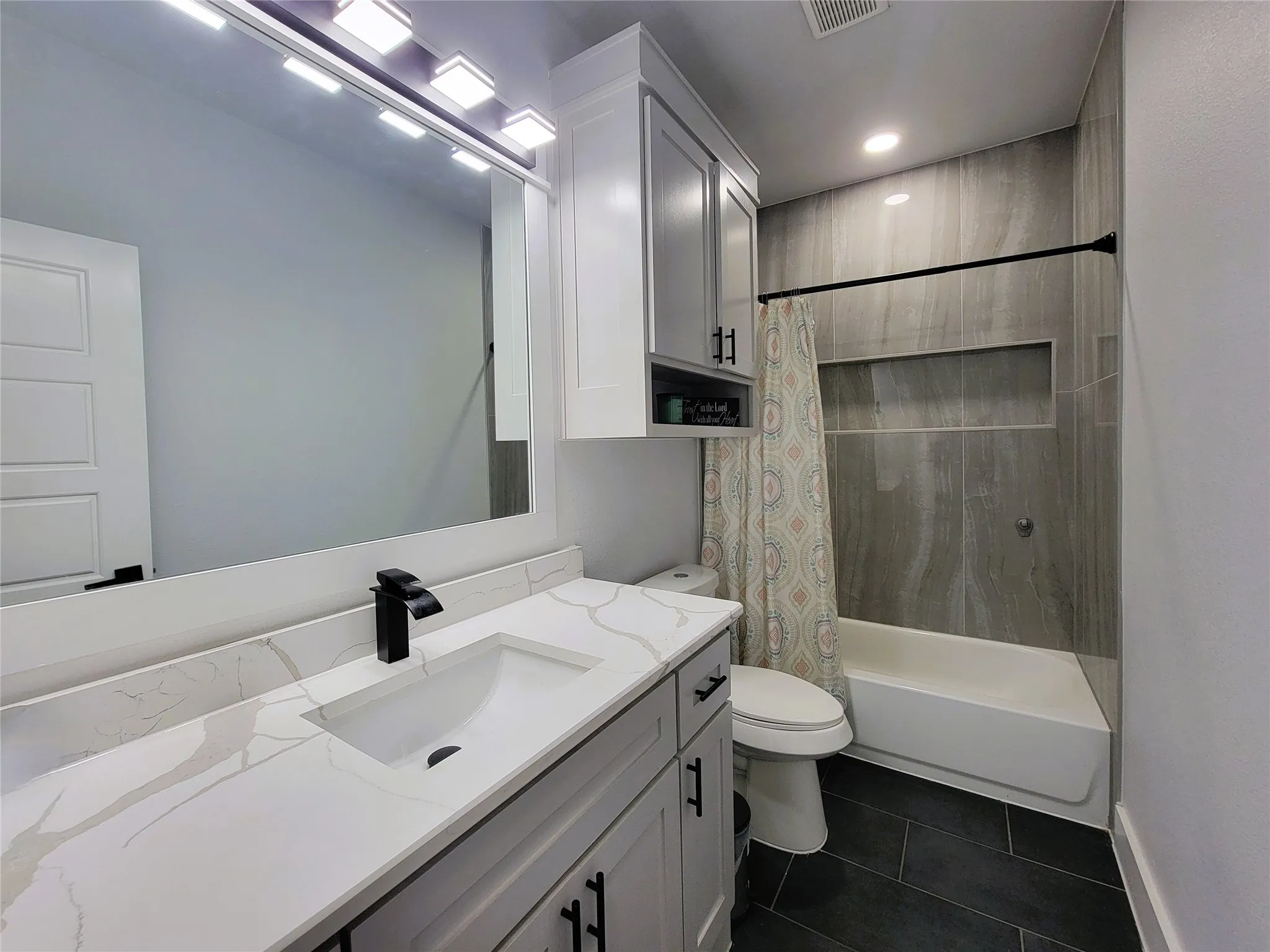 Built-in vanity with a single basin sink, white countertop, and matte black faucet