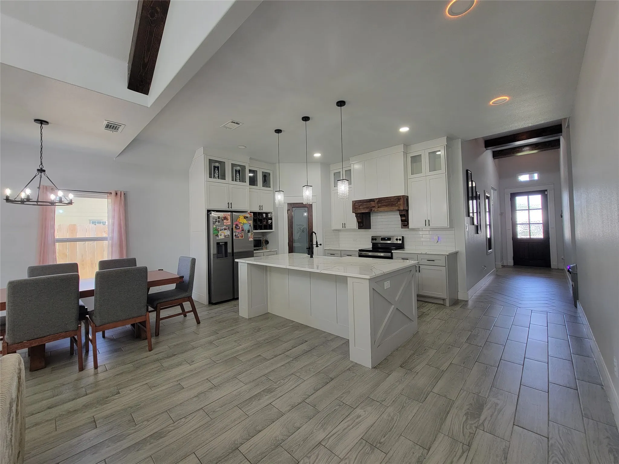 Kitchen featuring a central island with a stone countertop, white shaker cabinetry, and stainless-steel appliances