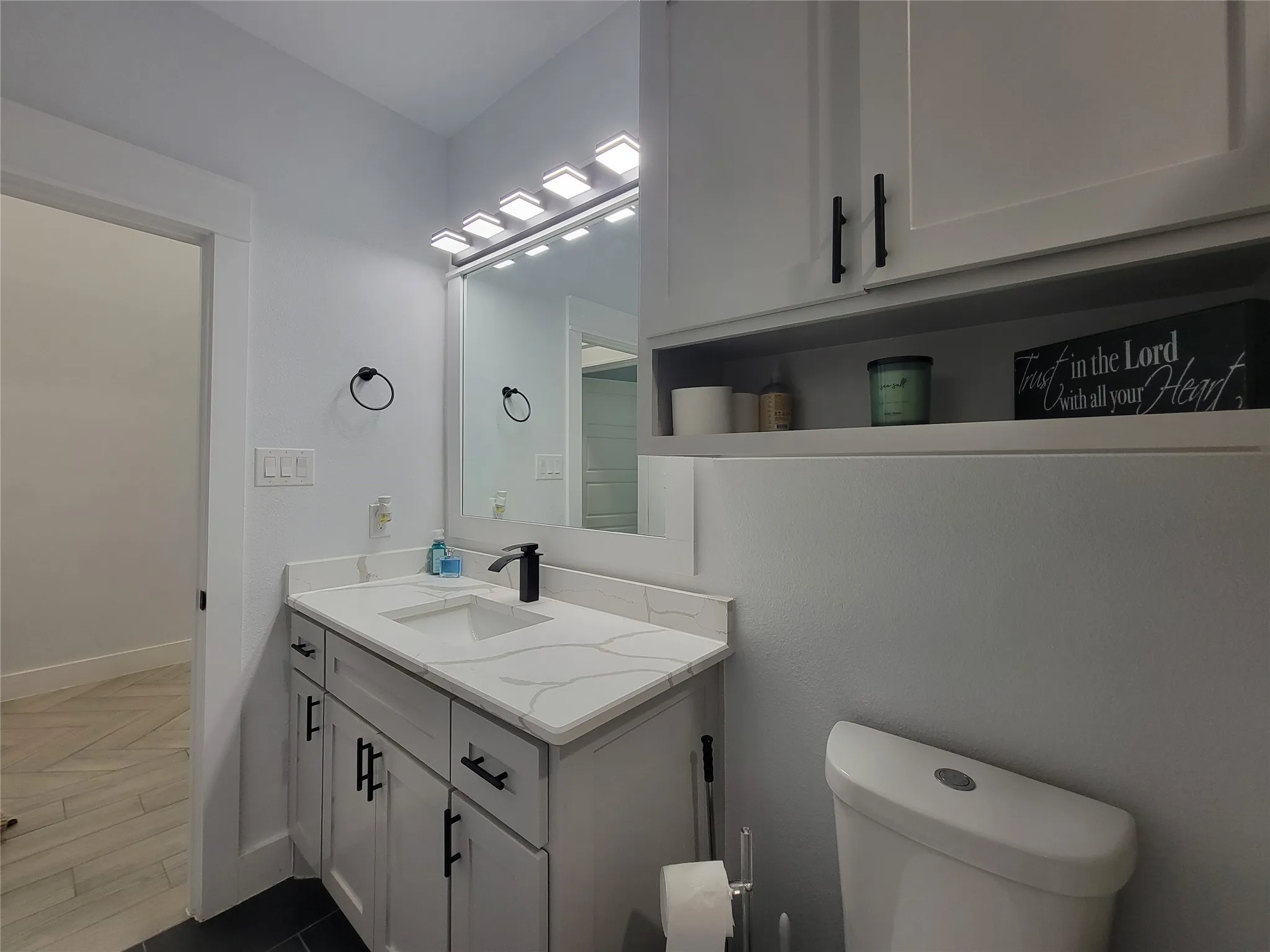 Vanity with a white countertop and integrated sink, black faucet, and white cabinetry