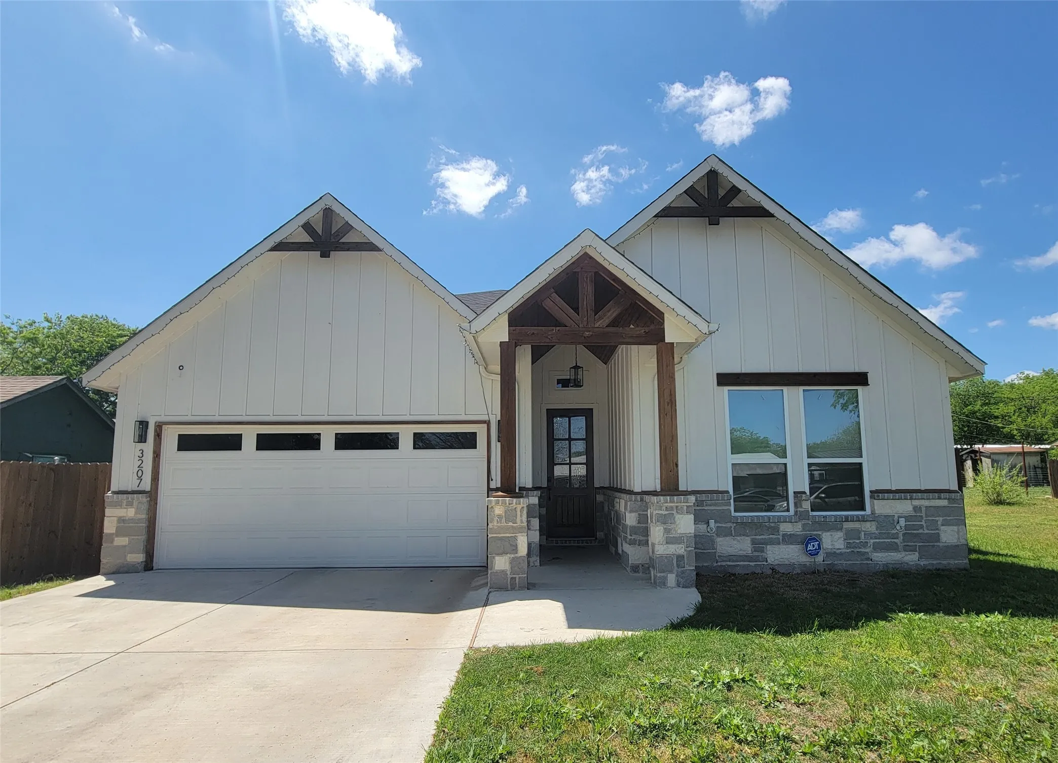 Modern farmhouse exterior with white board and batten siding, stone accents, and a covered entry