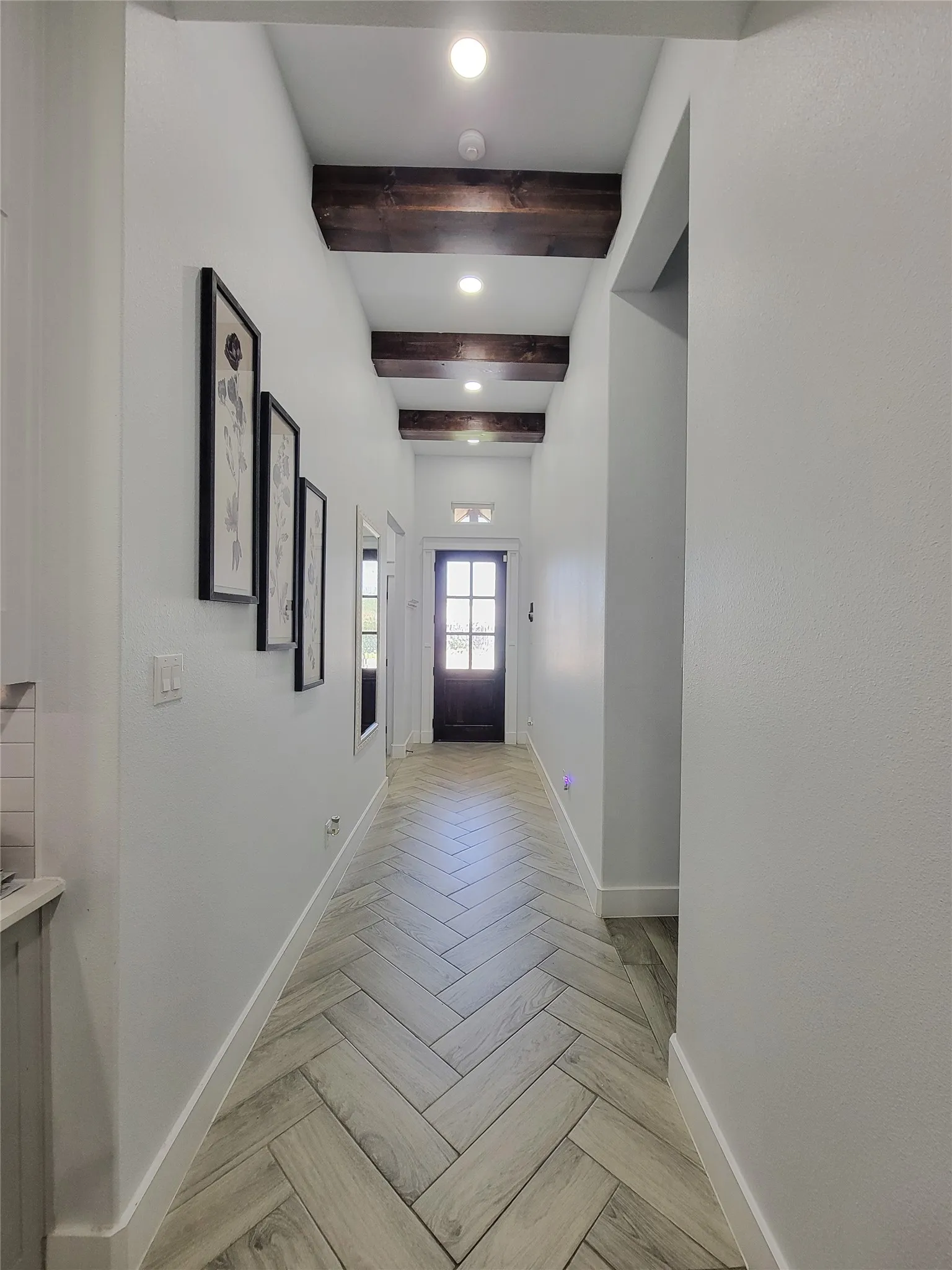 Hallway featuring recessed lighting, exposed wood beams, herringbone-patterned wood-finish flooring, and a paneled front door with glass inserts