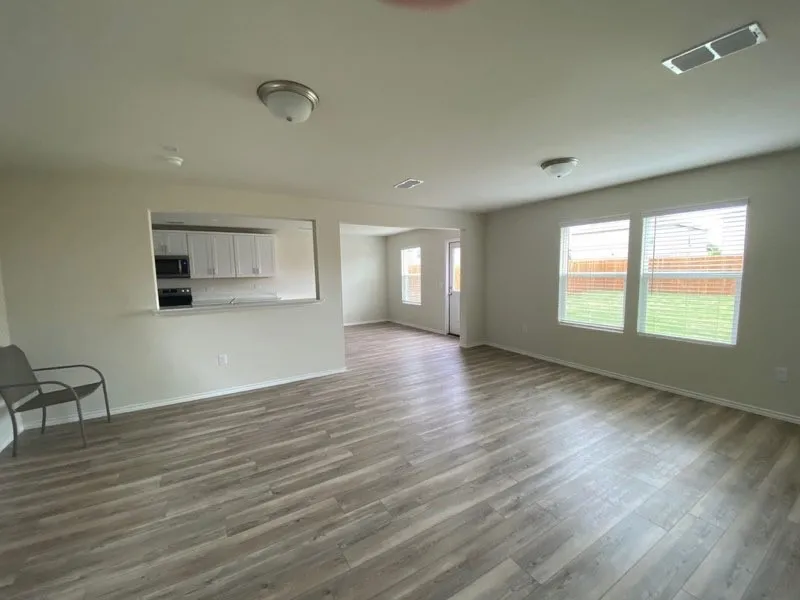 Open-concept living space featuring wood-finish flooring throughout, recessed ceiling lighting, and abundant natural light from large sliding glass doors and windows