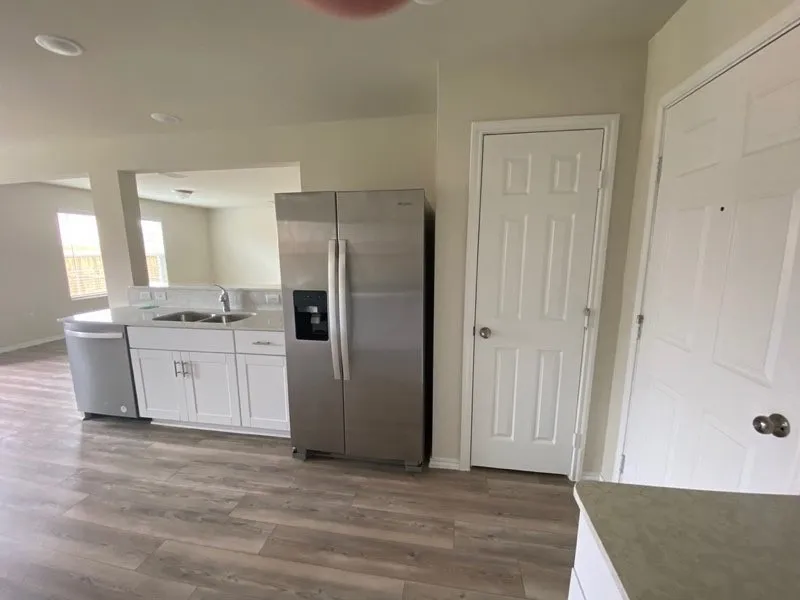 Kitchen featuring wood-finish flooring, white cabinetry, a double basin sink, and stainless steel appliances