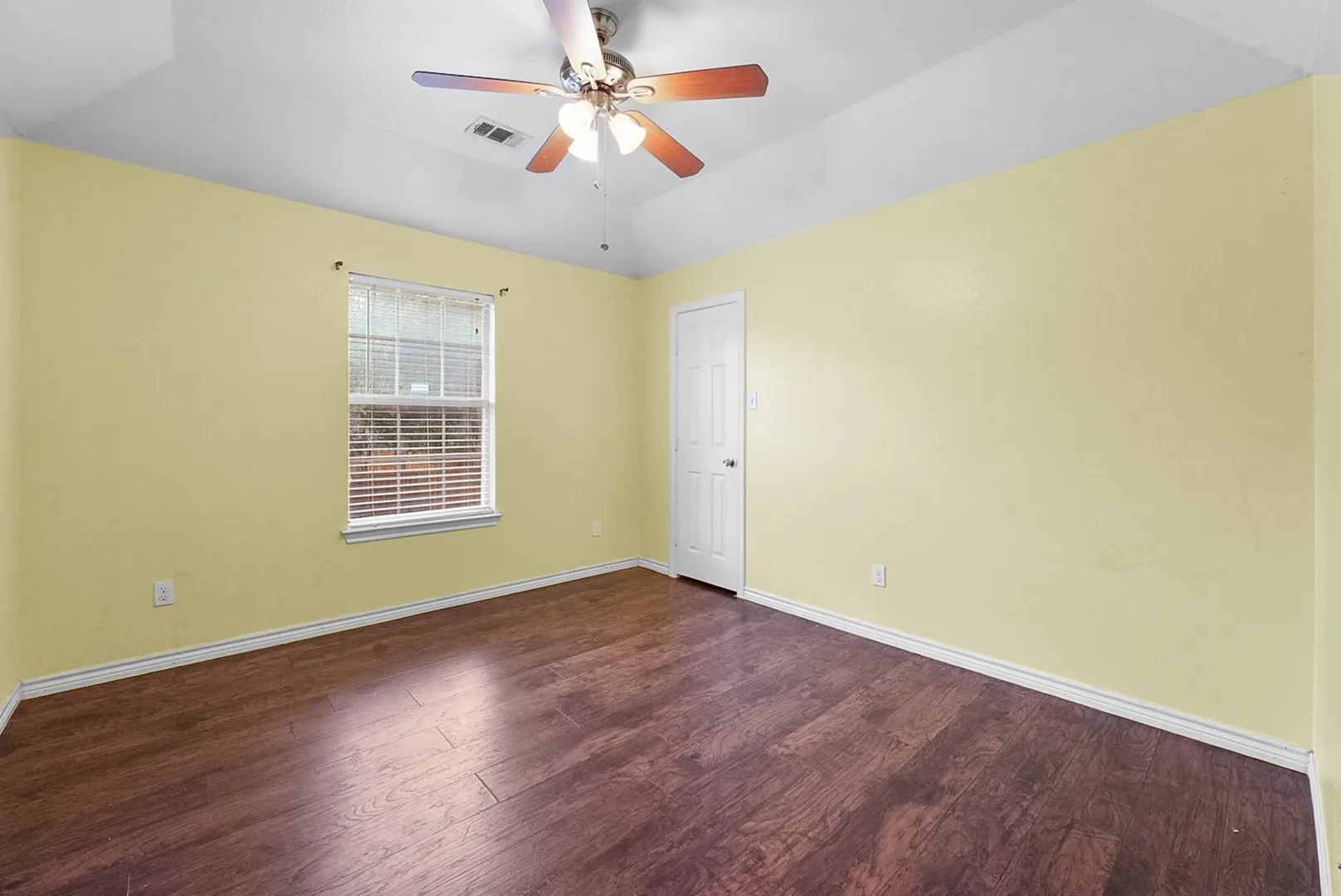 Vaulted ceiling featuring a ceiling fan with integrated lighting, wood-finish flooring, and natural light from the window