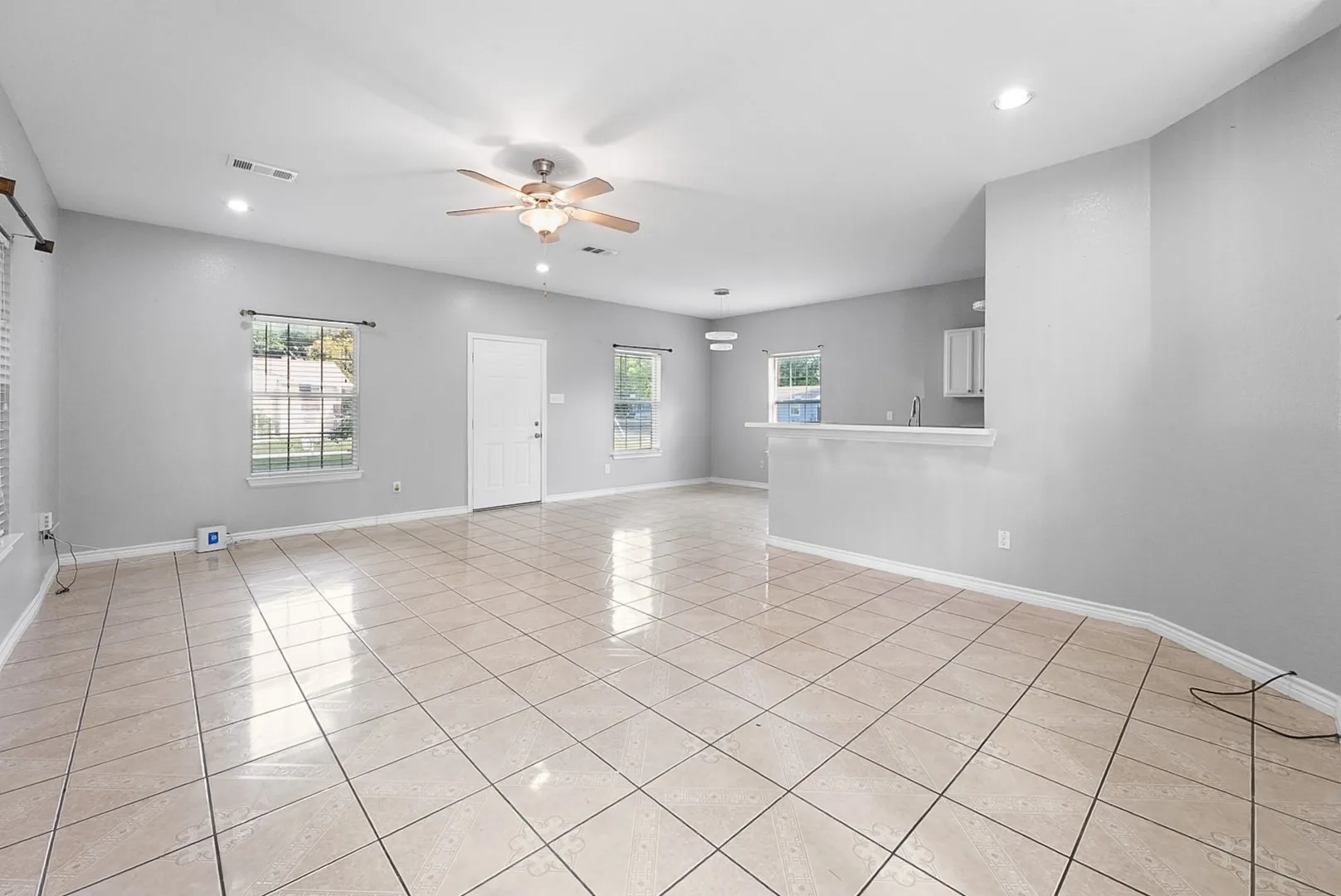 Expansive open-concept room featuring neutral paint, tiled flooring, recessed lighting, and a ceiling fan