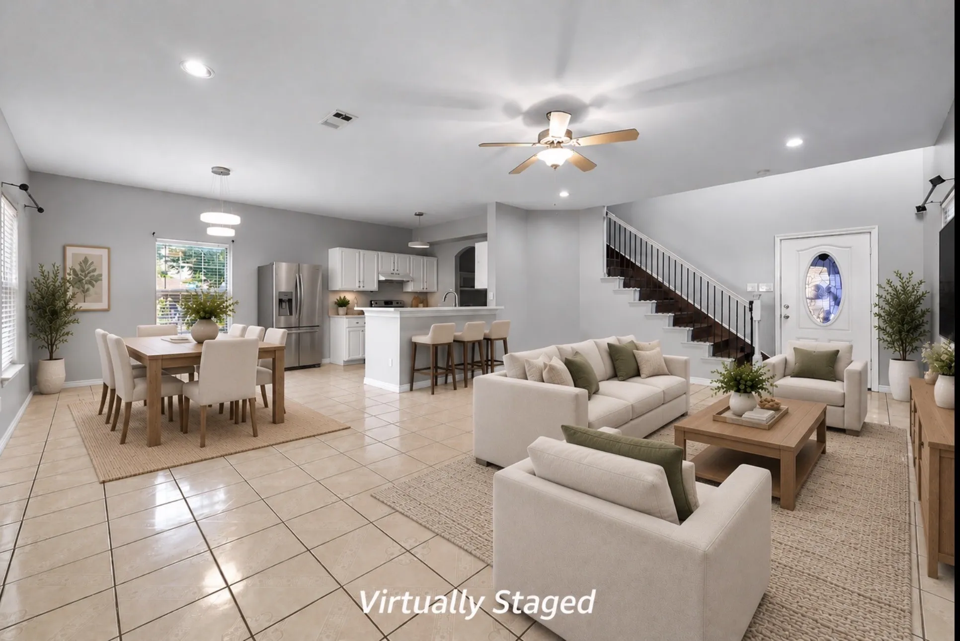 Tiled flooring throughout, kitchen with white cabinetry and stainless steel appliances, open-concept layout, recessed lighting, and a prominent staircase with white railings