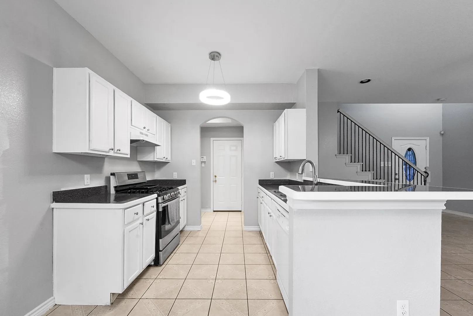 Kitchen featuring white cabinetry, dark countertops, tile flooring, stainless steel range, and a breakfast bar peninsula