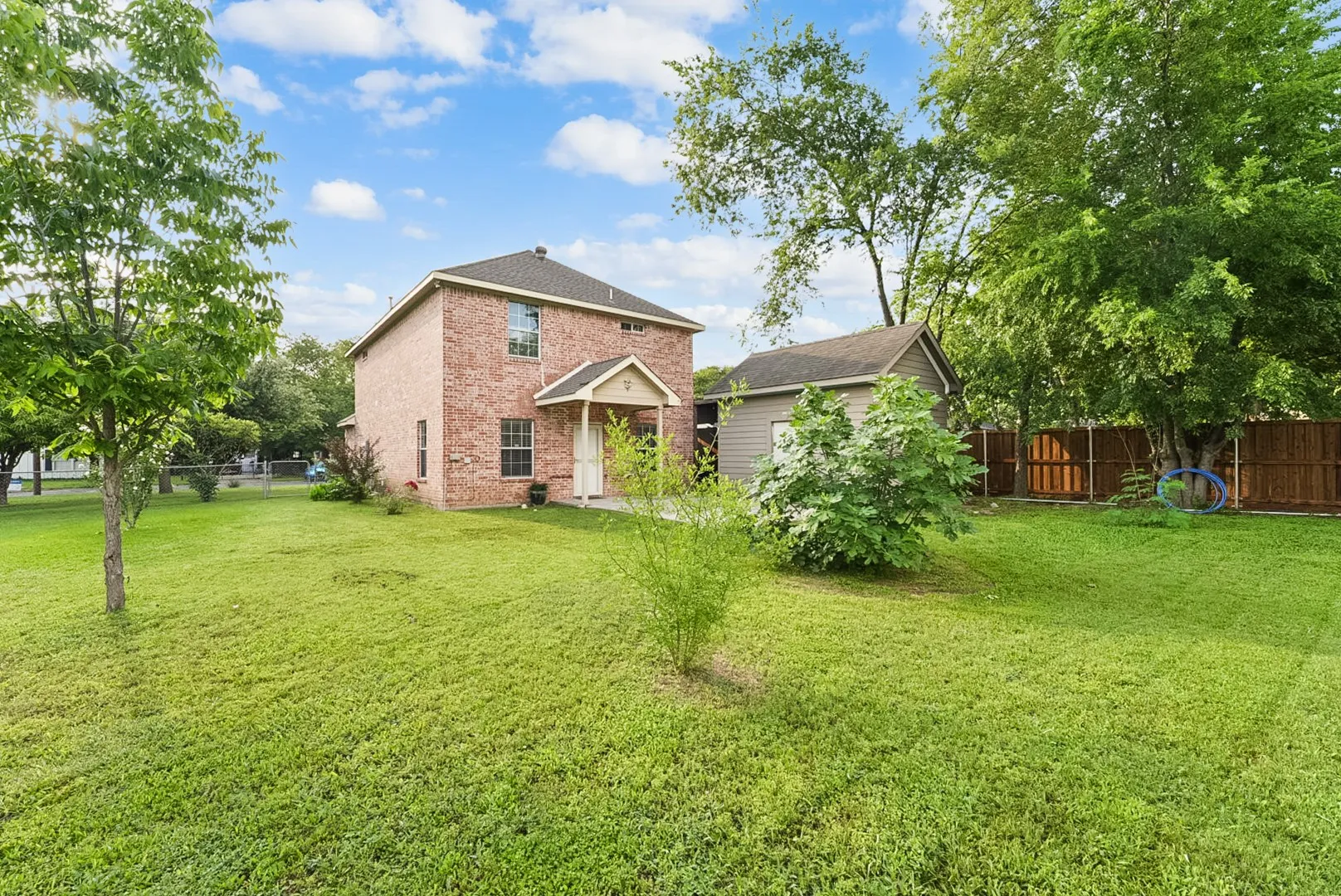 Brick exterior residence featuring a covered entry and a detached utility building
