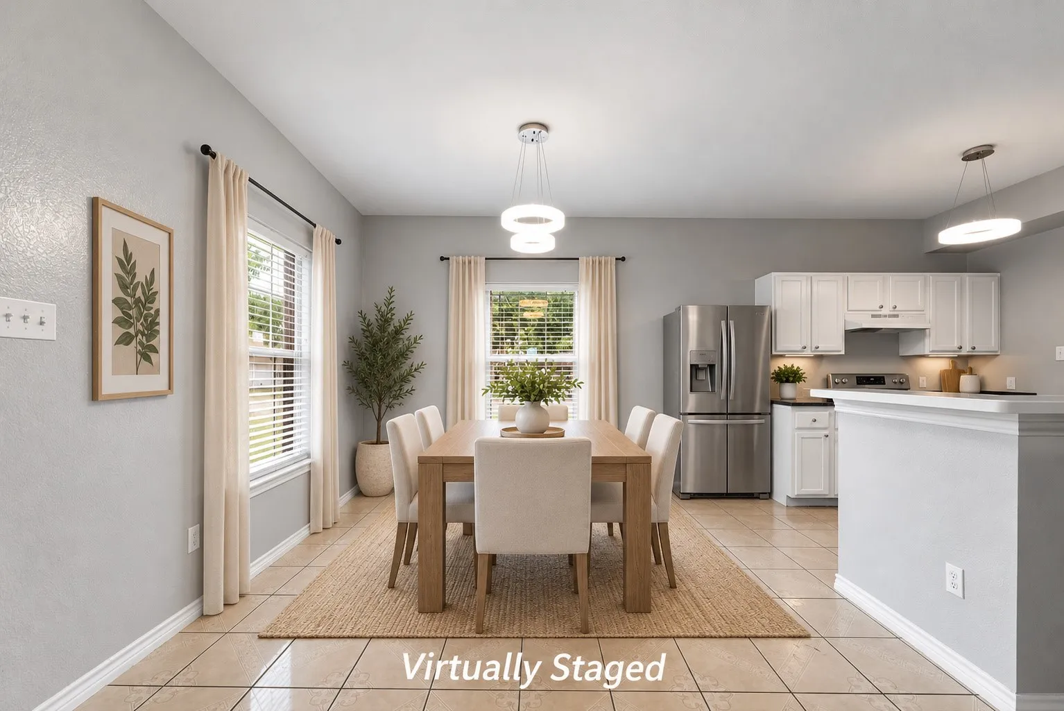 Open-concept living space with tile flooring, white cabinetry, stainless steel appliances, and dual pendant lighting fixtures