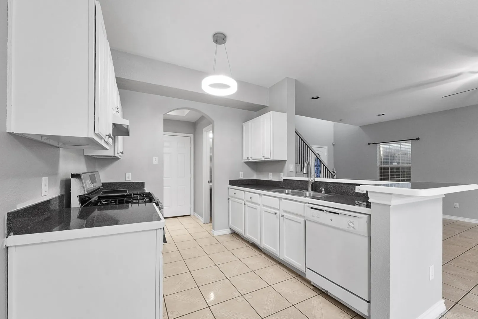 Kitchen featuring white cabinetry, dark countertops, a built-in dishwasher, a gas range, and tile flooring