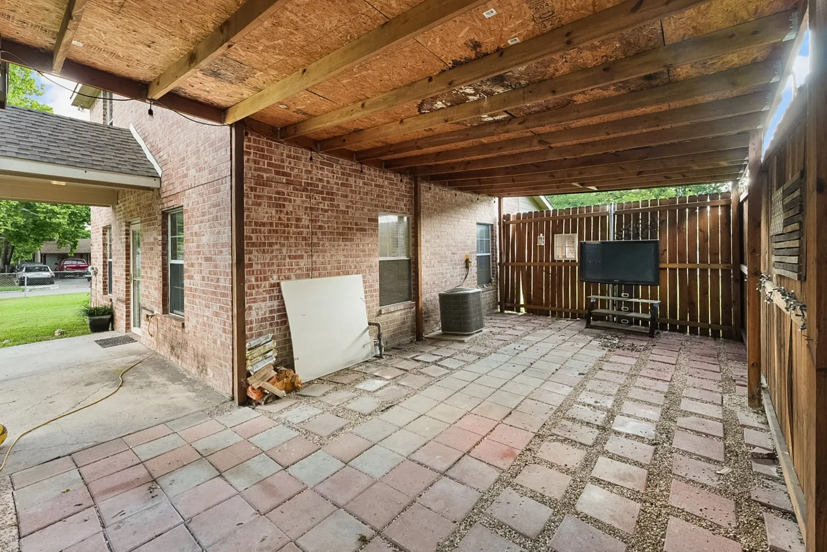 Covered patio with a wood beam ceiling and brick exterior